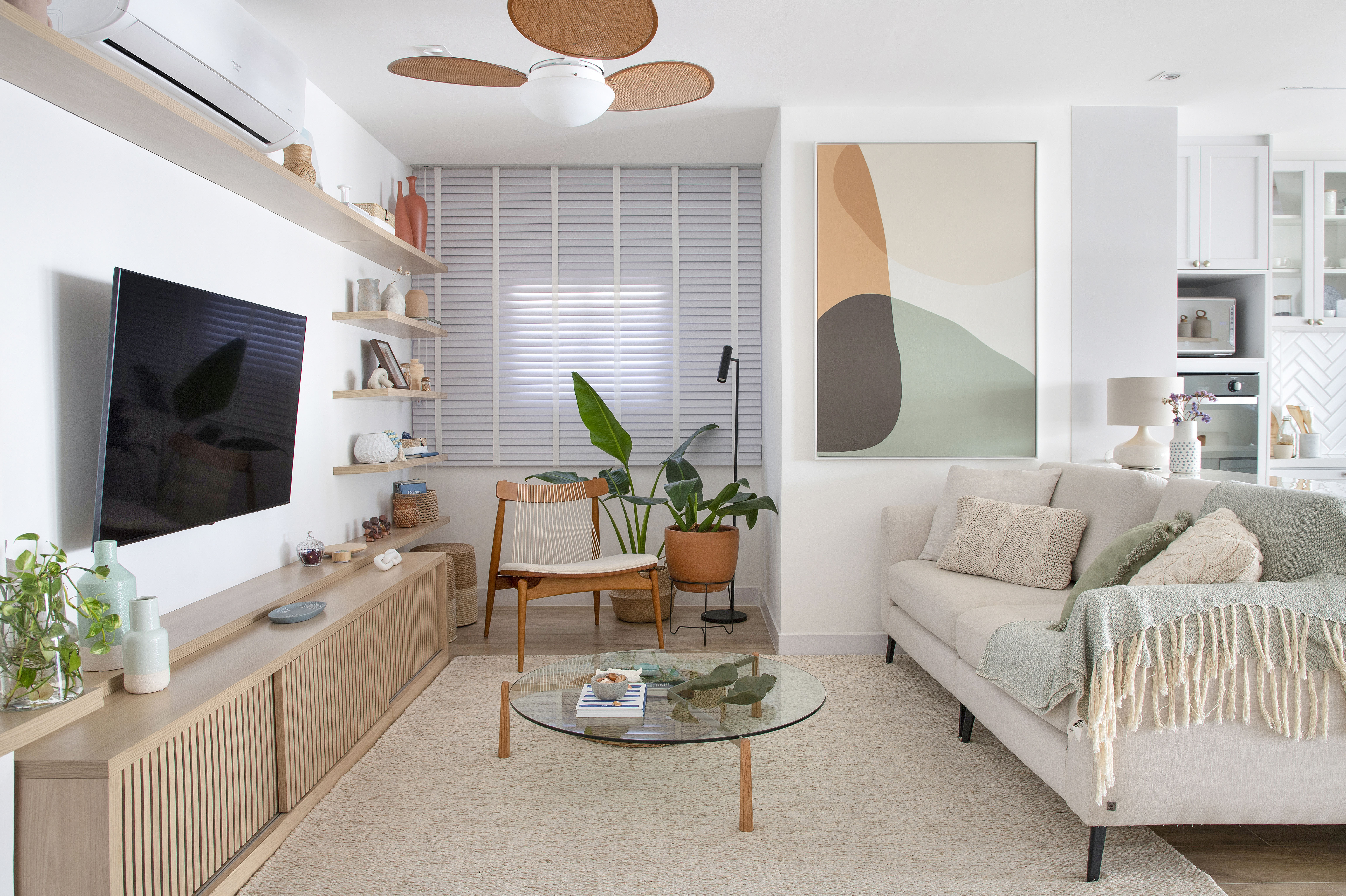 Duplex de 210 m² ganha décor na cor branca no estilo clássico e boho. Projeto de Amanda Miranda. Na foto, sala de estar com tv, quadro, sofá e tapete.