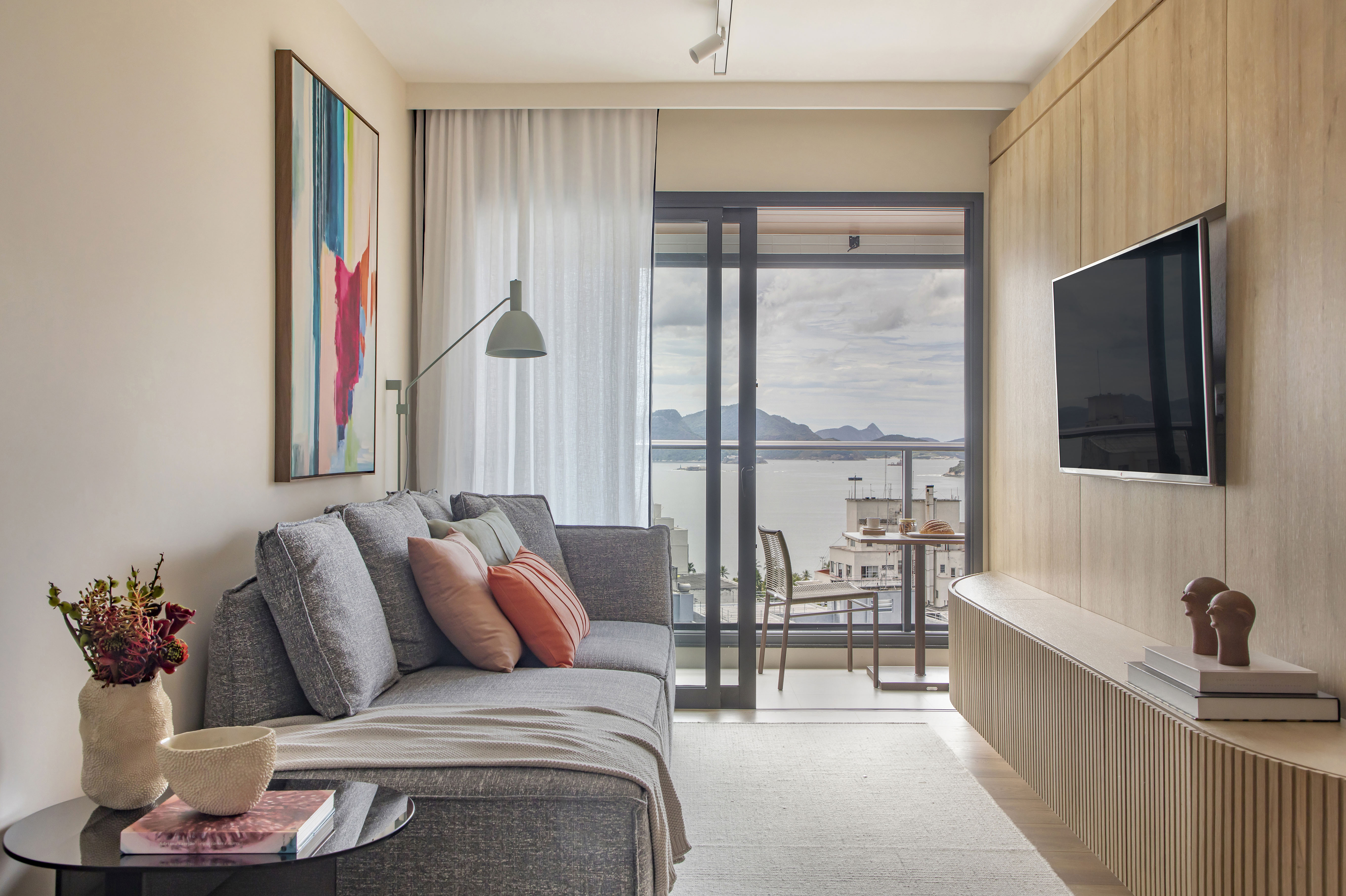 Apê de 65 m²: compacto, prático e com vista para a Baía da Guanabara. Projeto de Fabricio Ravaglia. Na foto, varanda com teto amadeirado e espaço de refeições. Sala com Tv e parede madeirada.