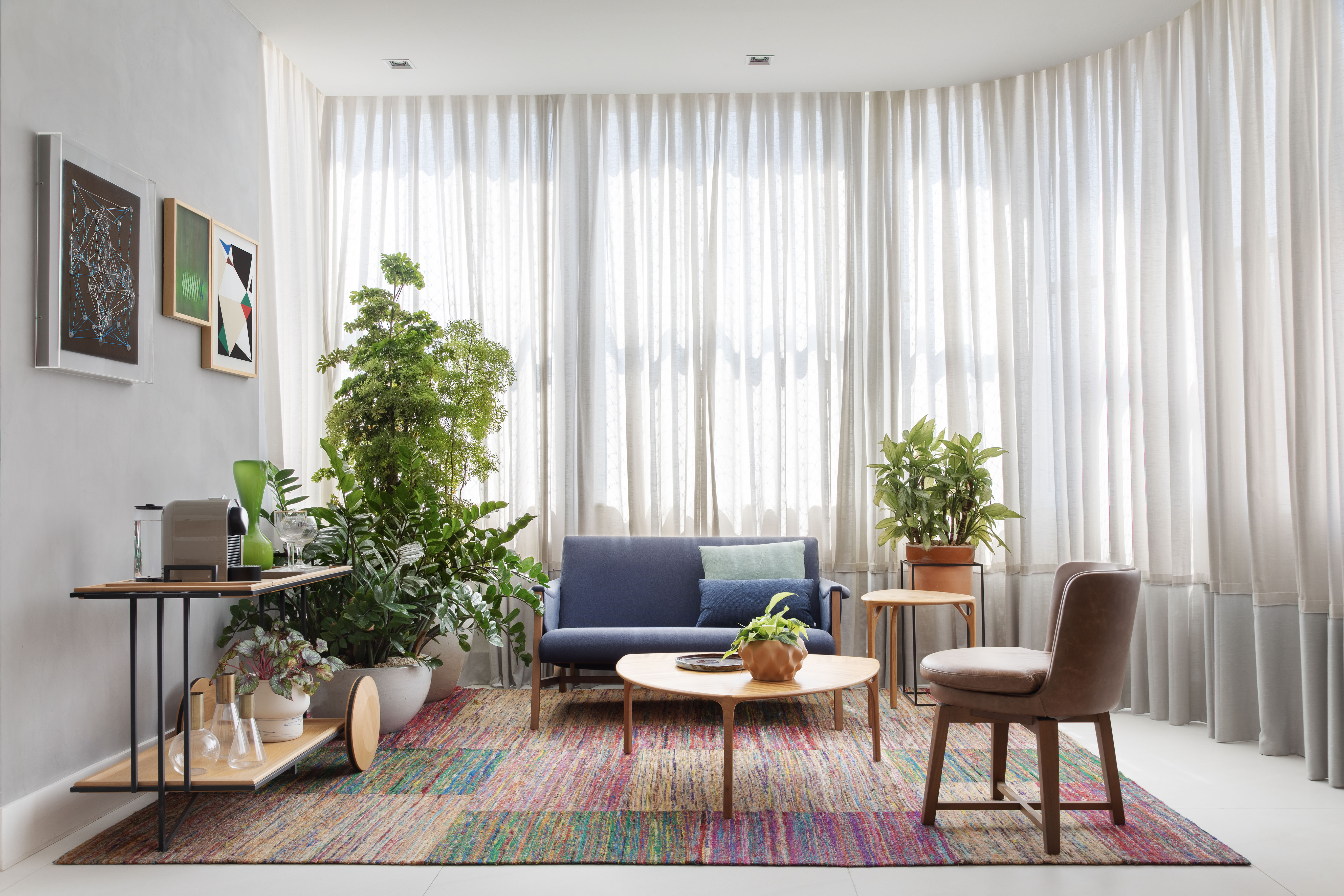 Décor atemporal, layout aberto e design brasileiro marcam apê de 210 m². Projeto de Bezamat Arquitetura, Na foto, sala com canto do café, cortinas e plantas.