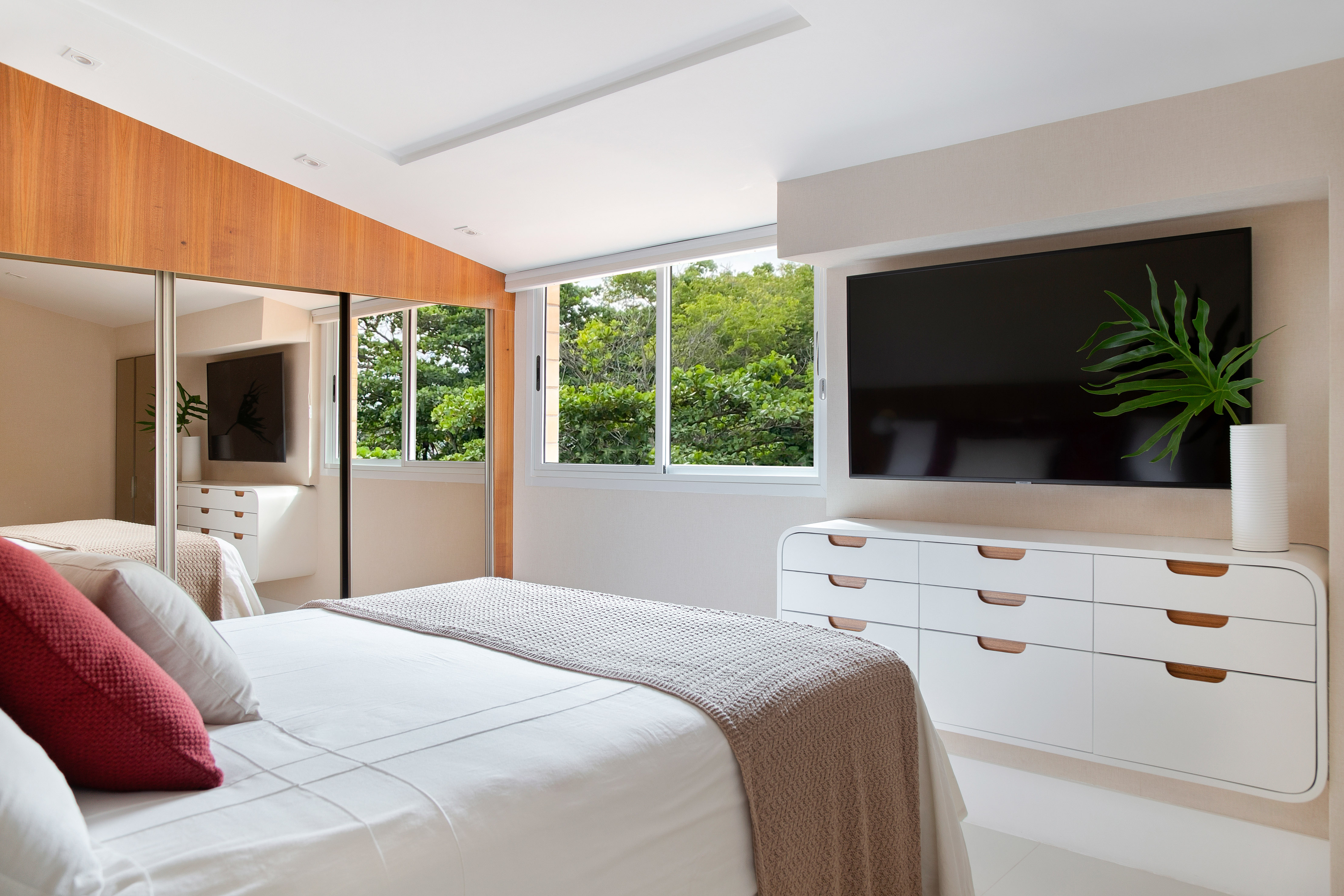 Sem quebra-quebra, apê de 130 m² no Rio ganha décor cozy e minimalista. Projeto Travessa Arquitetura. Na foto, quarto com tv e rack com desenho curvo.