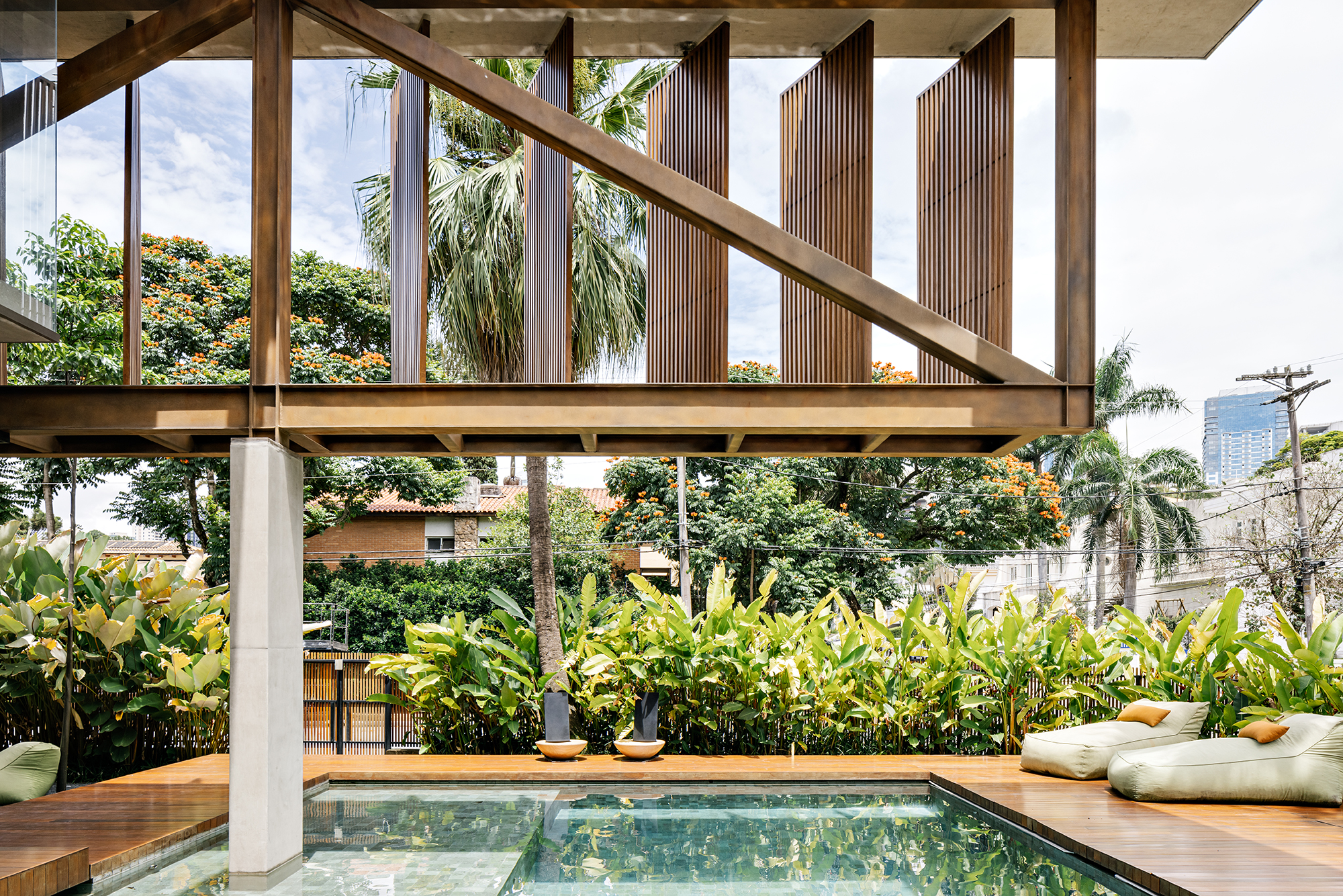 Treliça metálica de 22 m parece flutuar em frente à esta casa de 1275 m². Projeto de FGMF. Na foto, fachada da casa com jardim e piscina.