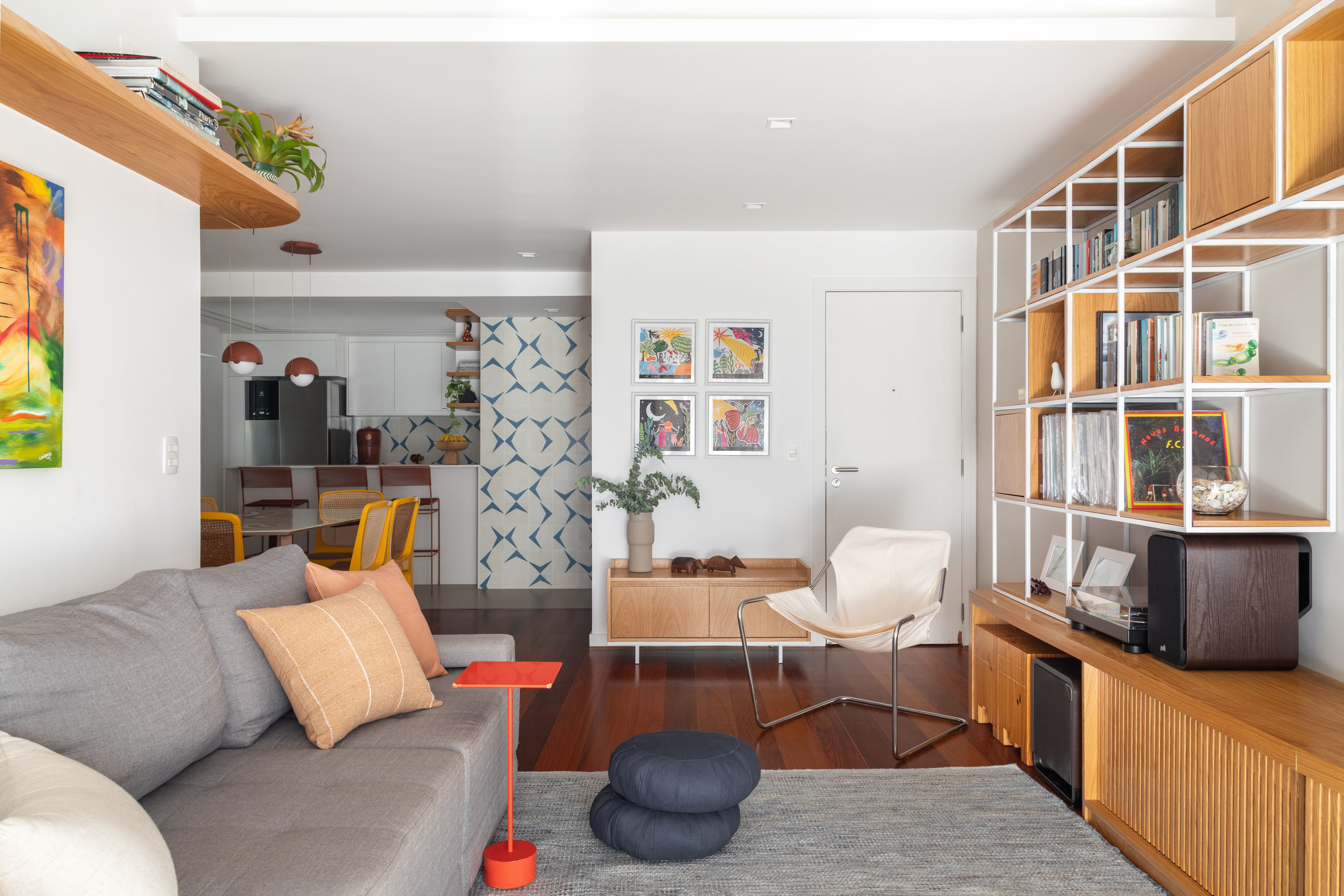 Apê de 120 m² vira o lar ideal para a família com duas filhas e dois gatos. Projeto de Co+Lab Juntos Arquitetura e Interiores. Na foto, sala de estar com sofá, poltrona, quadros e tapete.