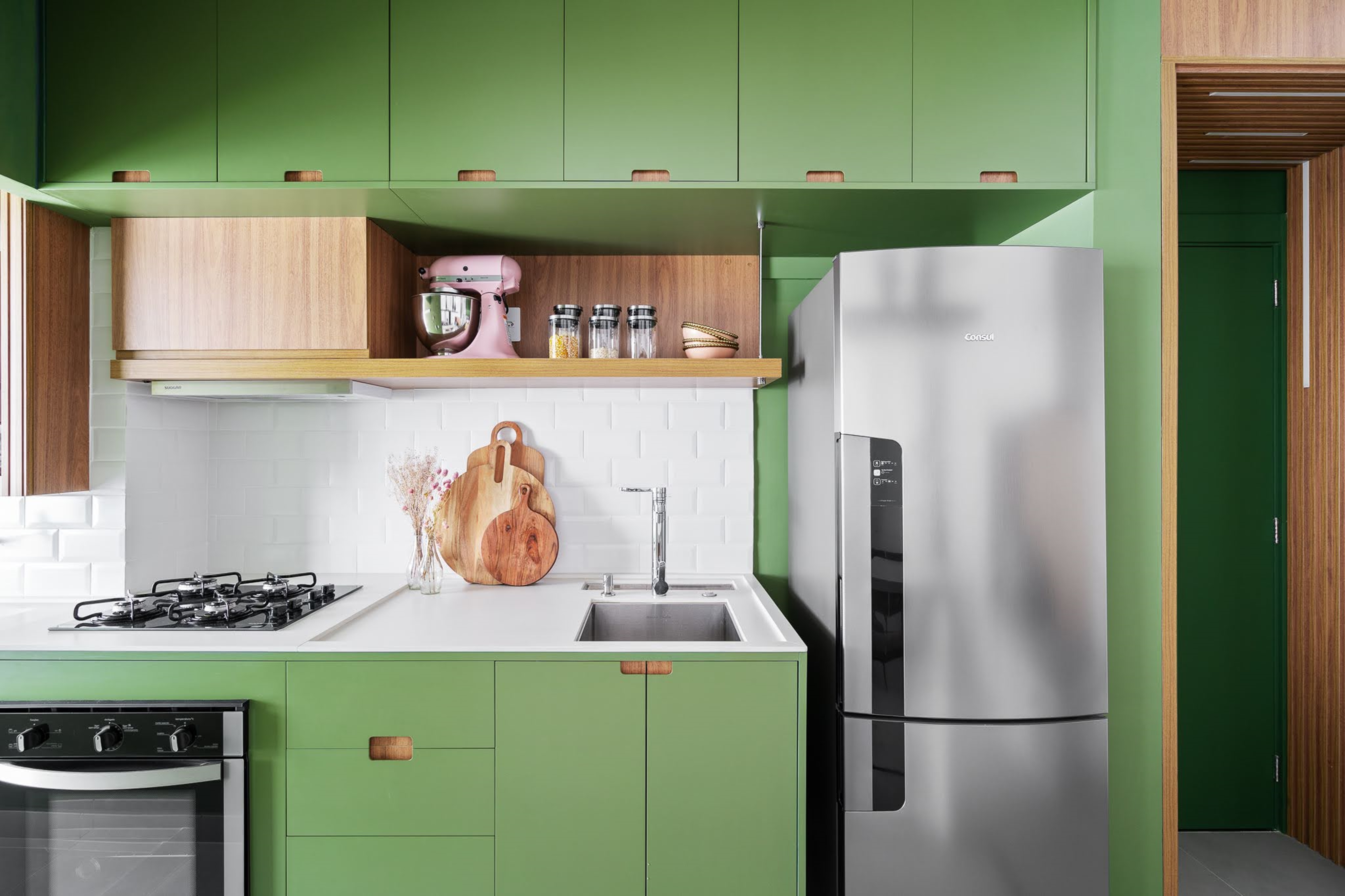 Cozinha verde e detalhes coloridos personalizam apê de 49 m². Projeto de Natalia Salla. Na foto, cozinha com marcenaria verde e balcão de refeições.