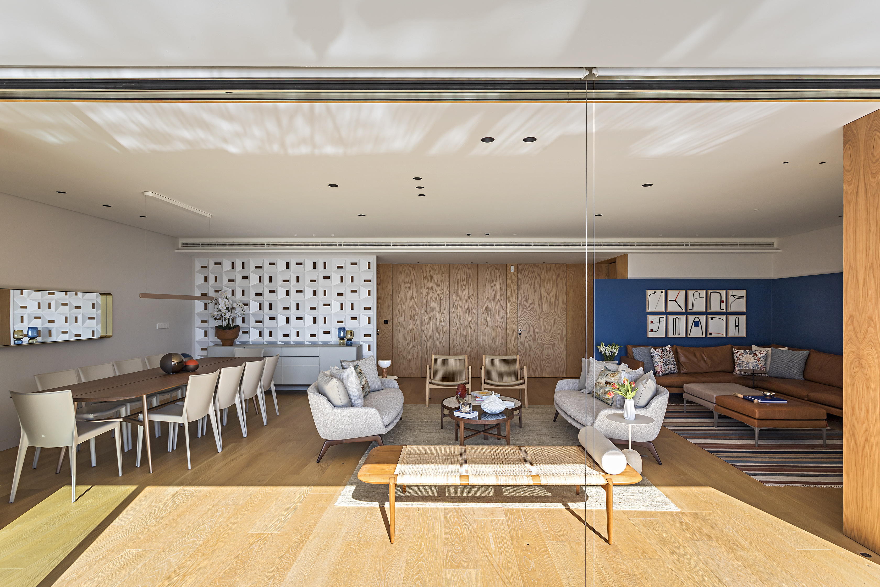 Apê contemporâneo fica em antiga propriedade real portuguesa. Projeto de Andrea Chicharo. Na foto, sala de jantar com parede de cobogós e quadro. Estar com quadros, sofá e poltronas.