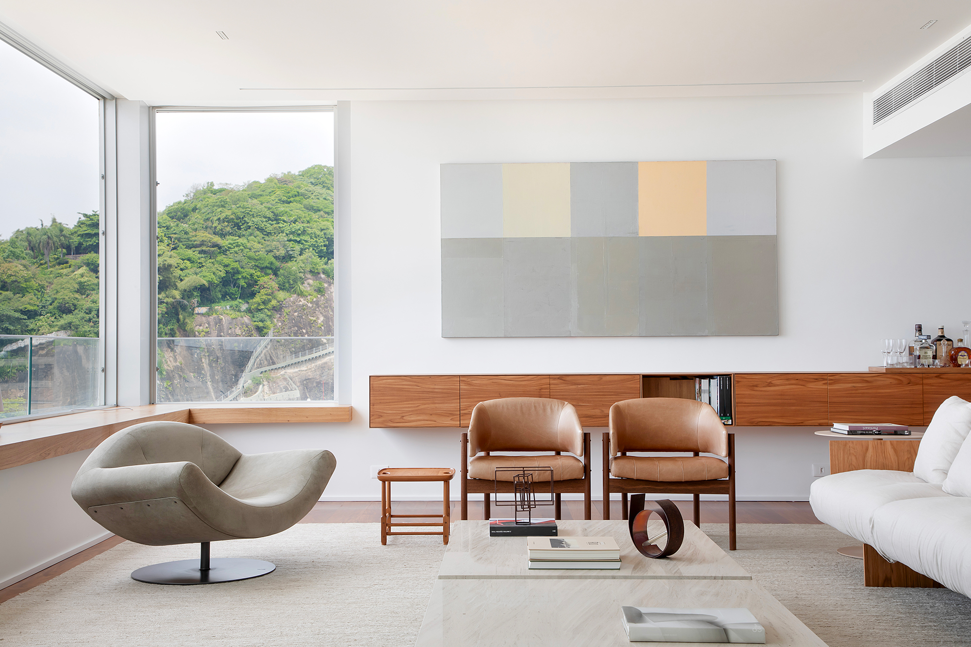 À beira-mar, apartamento minimalista ganha ares de galeria de arte. Projeto de João Panaggio. Na foto, sala de estar com quadro, aparador-bar, poltronas e sofá.