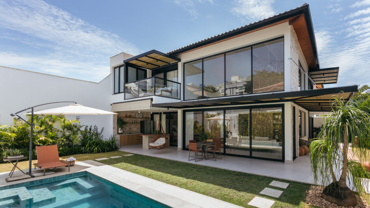 Casa de praia 195 m² feita do zero une natureza, surfe e ciclismo. Projeto de Amanda Miranda. Na foto, fachada com piscina, jardim e varanda.