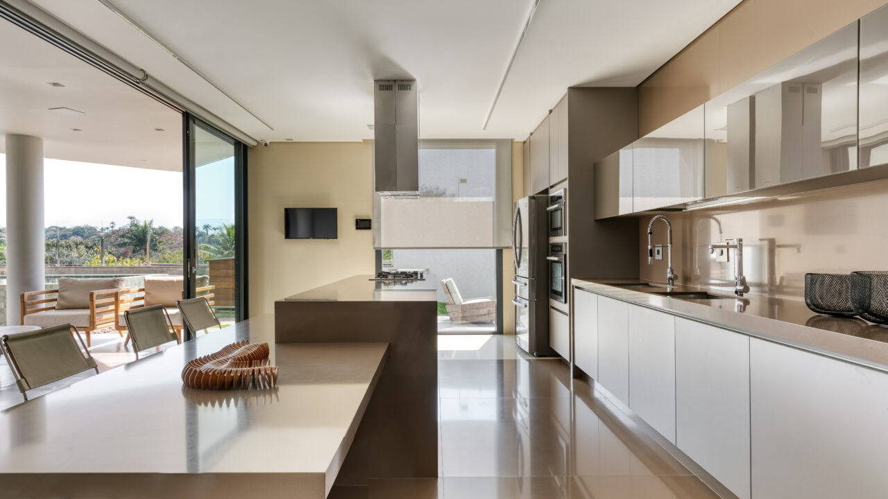 Com vista para a Pampulha, casa de 600 m² é integrada à natureza. Projeto de Lucas Lage. Na foto, cozinha com ilha. torrente quente e armários espelhados.