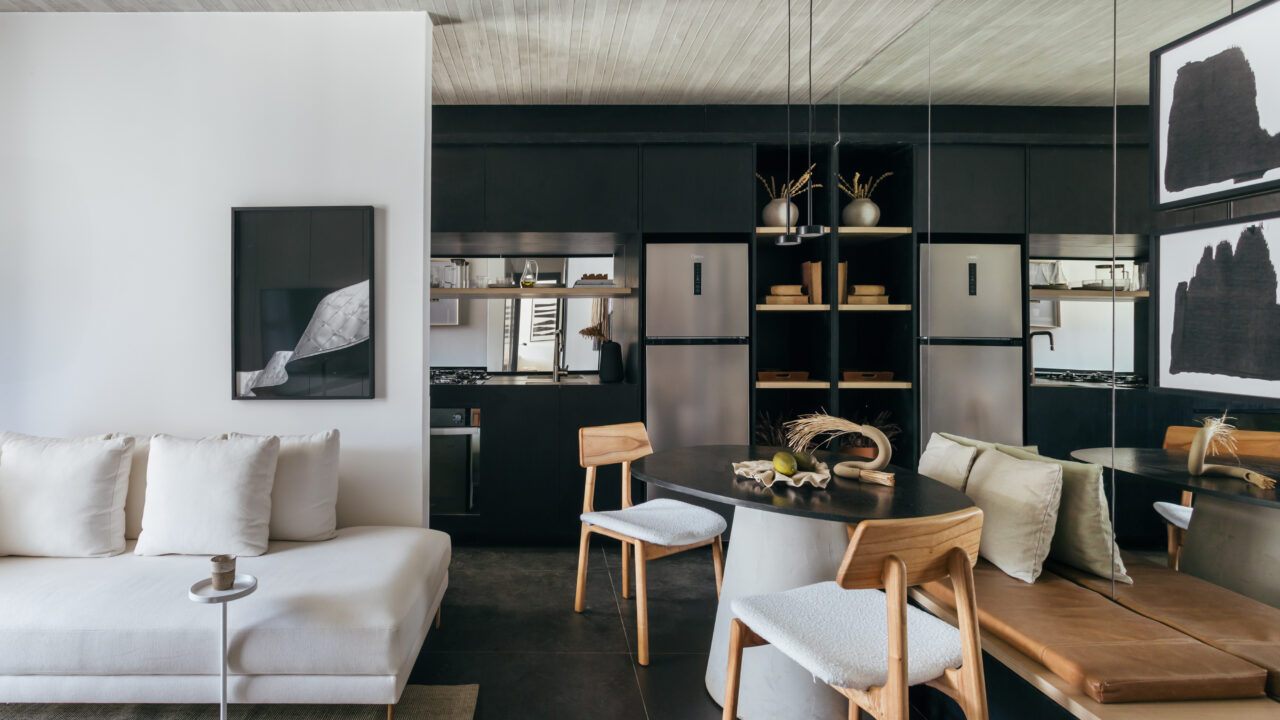 Com paleta preta e cinza, apê de 73 m² é decorado com móveis soltos. Projeto de Leandro Neves. Na foto, sala com marcenaria preta, sofá e banco.