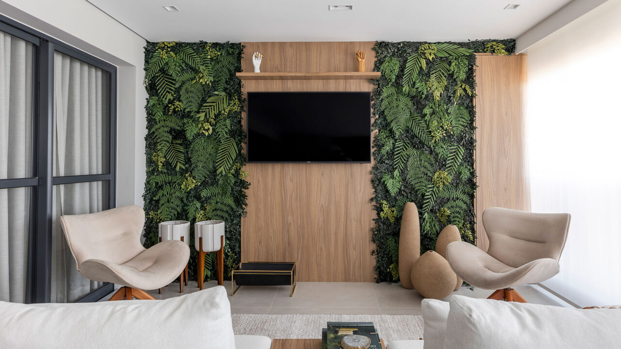 Blaia e Moura Arquitetos privilegia a integração neste apartamento em SP. Na foto, varanda com sofá, TV e jardim vertical.