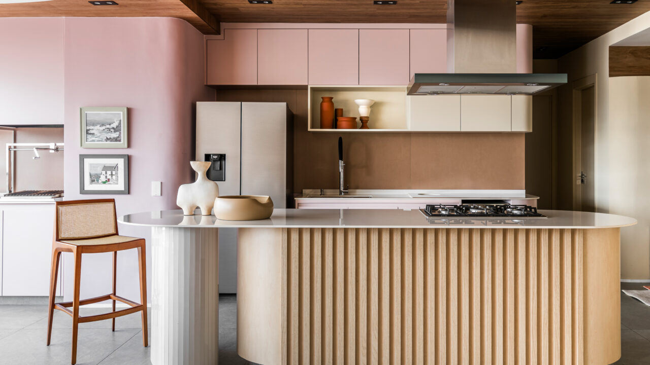 Cozinha rosa, plantas e curvas marcam apê assinado por Ricardo Abreu. Na foto, cozinha integrada à sala de TV, Marcenaria rosa e bancada,