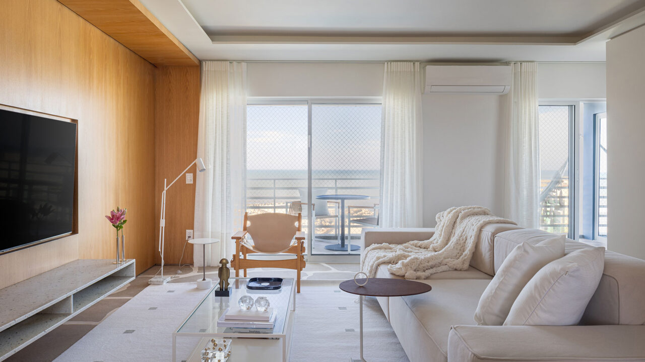 Apartamento de 89 m² vira refúgio náutico no litoral paranaense. Projeto de Rodolfo Fontana. Na foto, sala de estar com sofá, TV e tapete,