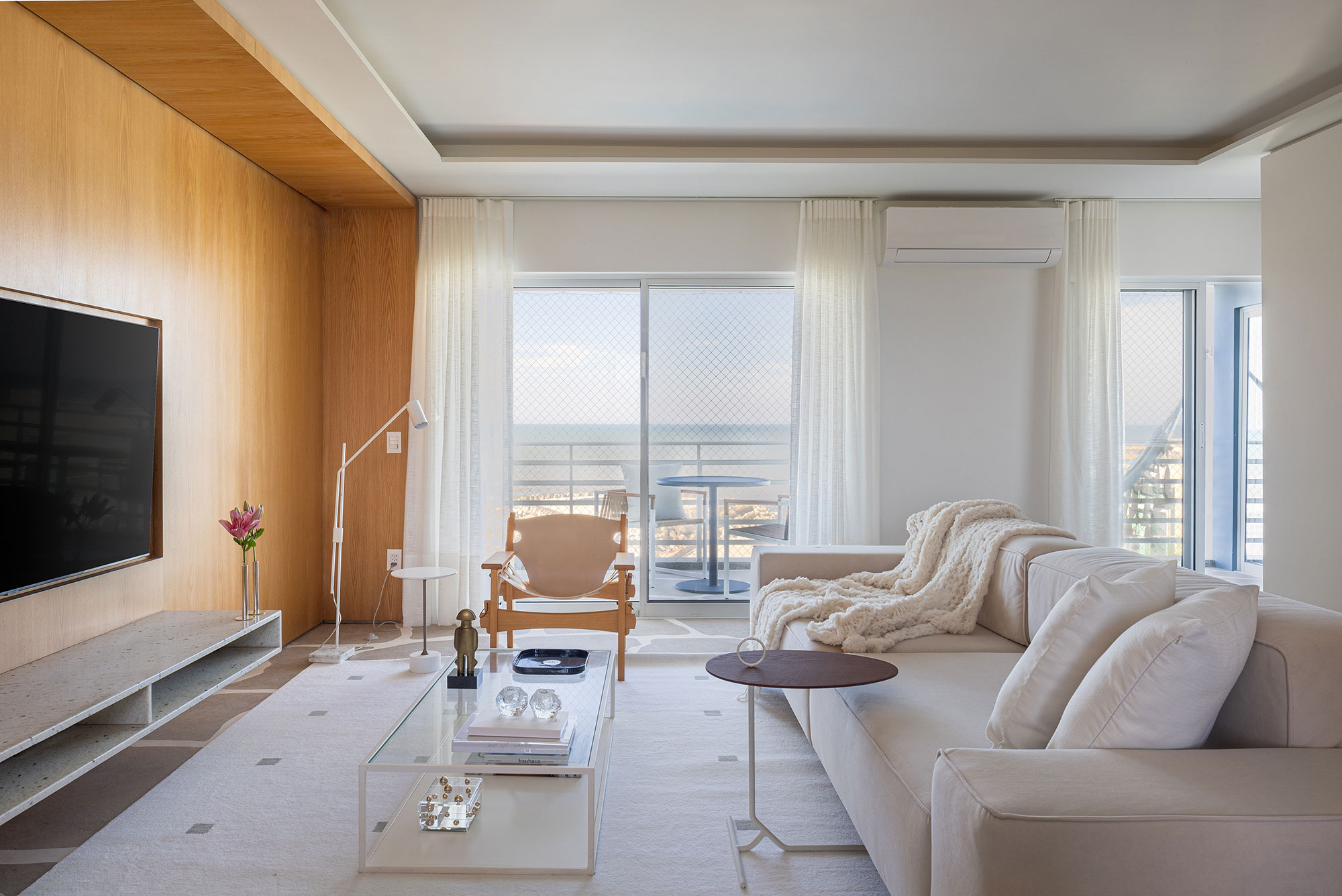 Apartamento de 89 m² vira refúgio náutico no litoral paranaense. Projeto de Rodolfo Fontana. Na foto, sala de estar com sofá, TV e tapete,