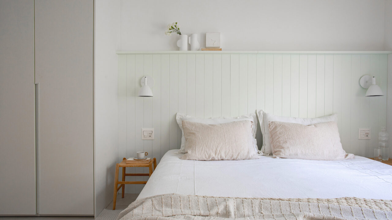 Casal de ingleses troca a casa na Inglaterra por apê minimalista no Rio. Projeto da arquiteta Natalia Lemos. Na foto, quarto de casal com cabeceira de madeira e cortinas.