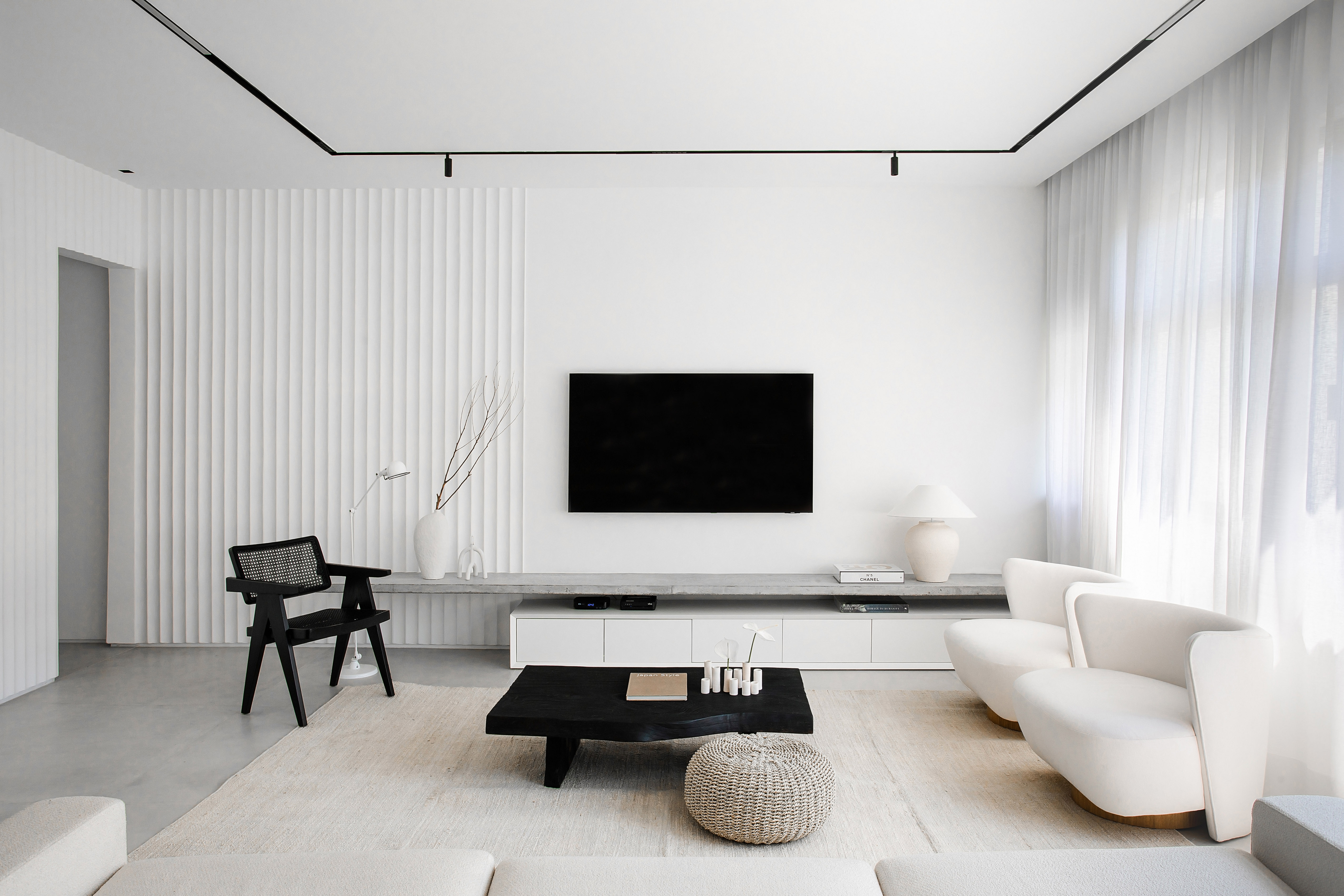 Casal de ingleses troca a casa na Inglaterra por apê minimalista no Rio. Projeto da arquiteta Natalia Lemos. Na foto, sala de estar com tv, parede branca e poltronas.