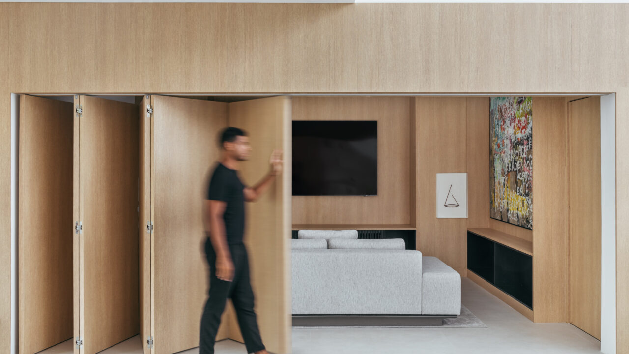 Conheça a casa de 750 m² do jogador de futebol André Balada. Projeto de Tom Castro. Na foto, sala de TV com porta camarão e parede de madeira.