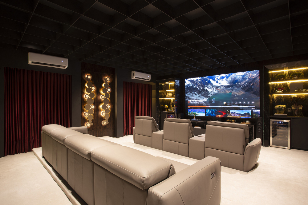 Home Cinema - No ambiente de Richard Gohr e Carolina Lopes, o cinza predomina no piso de placas cimentícias e no teto no tom Gray Marble, estruturado em steel frame com fechamento em placas acústicas. Junto com as paredes grafite, eles funcionam como pano de fundo para o mobiliário de marcas como Decameron, La Lampe e de designers como Sergio Rodrigues e Marcos Ferreira. A mesa lateral, o pendente e o sofá foram desenvolvidos pelo arquiteto Richard Gohr.