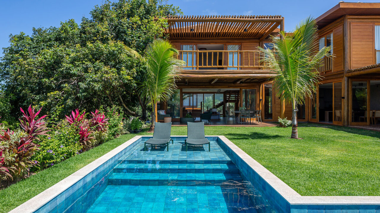 Casa na praia se integra à natureza com venezianas móveis na fachada. Projeto de Sidney Quintela. Na foto, varanda com pergolado e piscina.