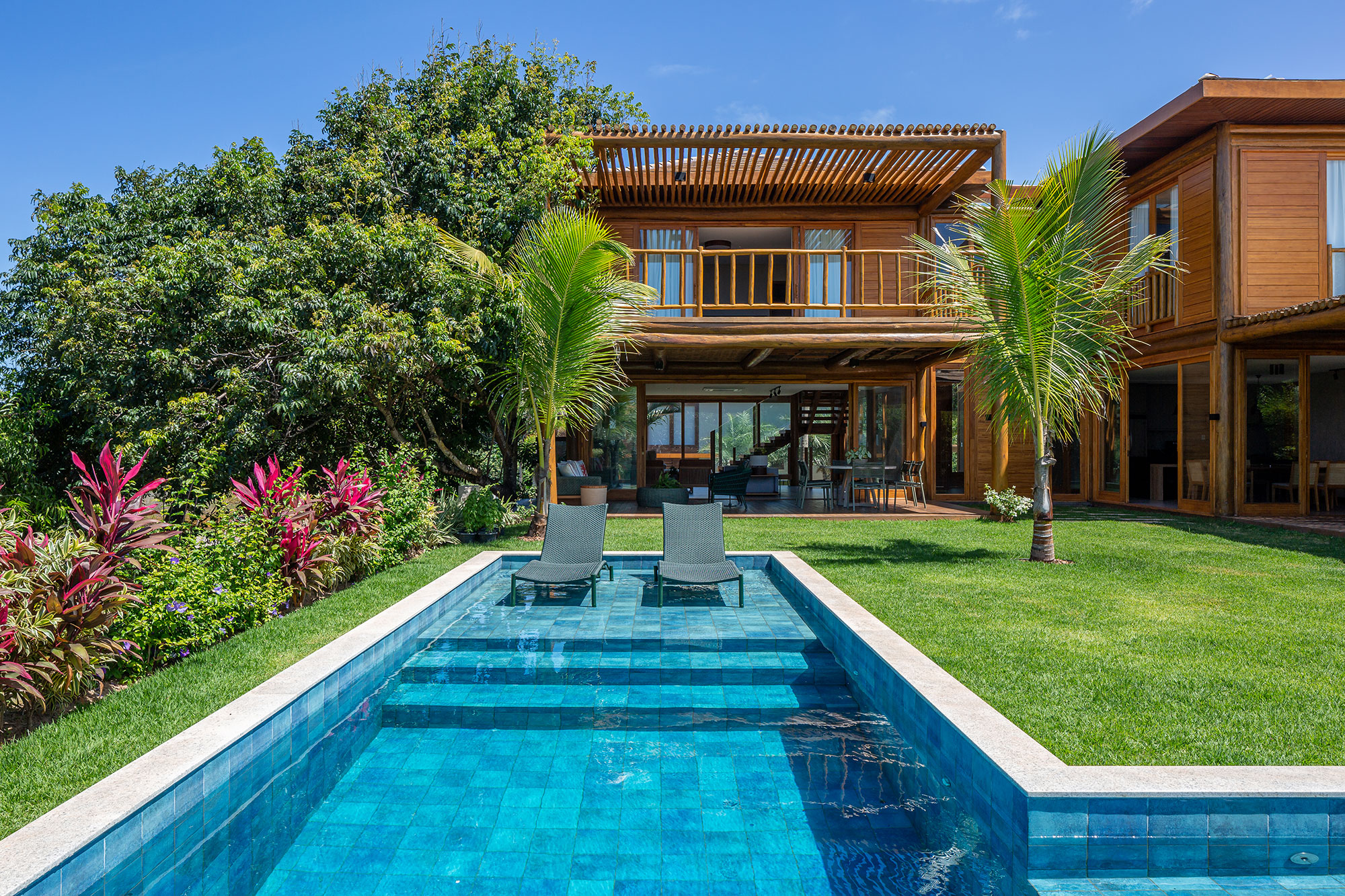 Casa na praia se integra à natureza com venezianas móveis na fachada. Projeto de Sidney Quintela. Na foto, varanda com pergolado e piscina.