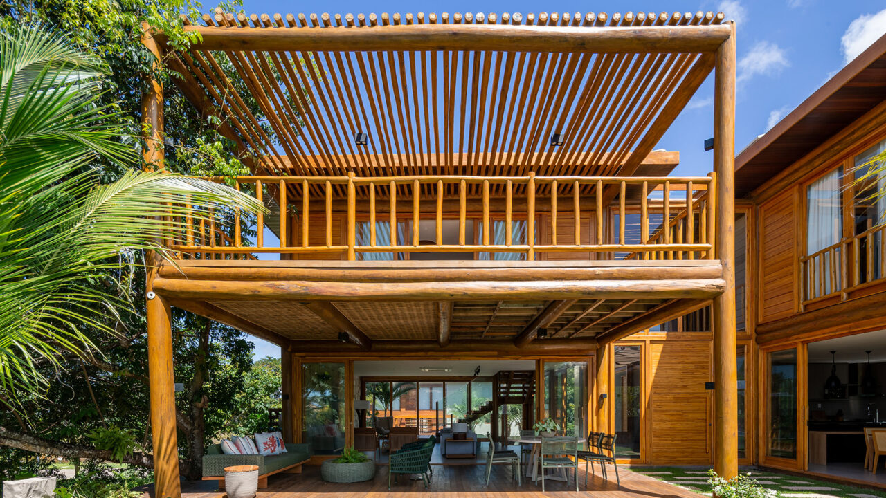 Casa na praia se integra à natureza com venezianas móveis na fachada. Projeto de Sidney Quintela. Na foto, varanda com jardim e pergolado.