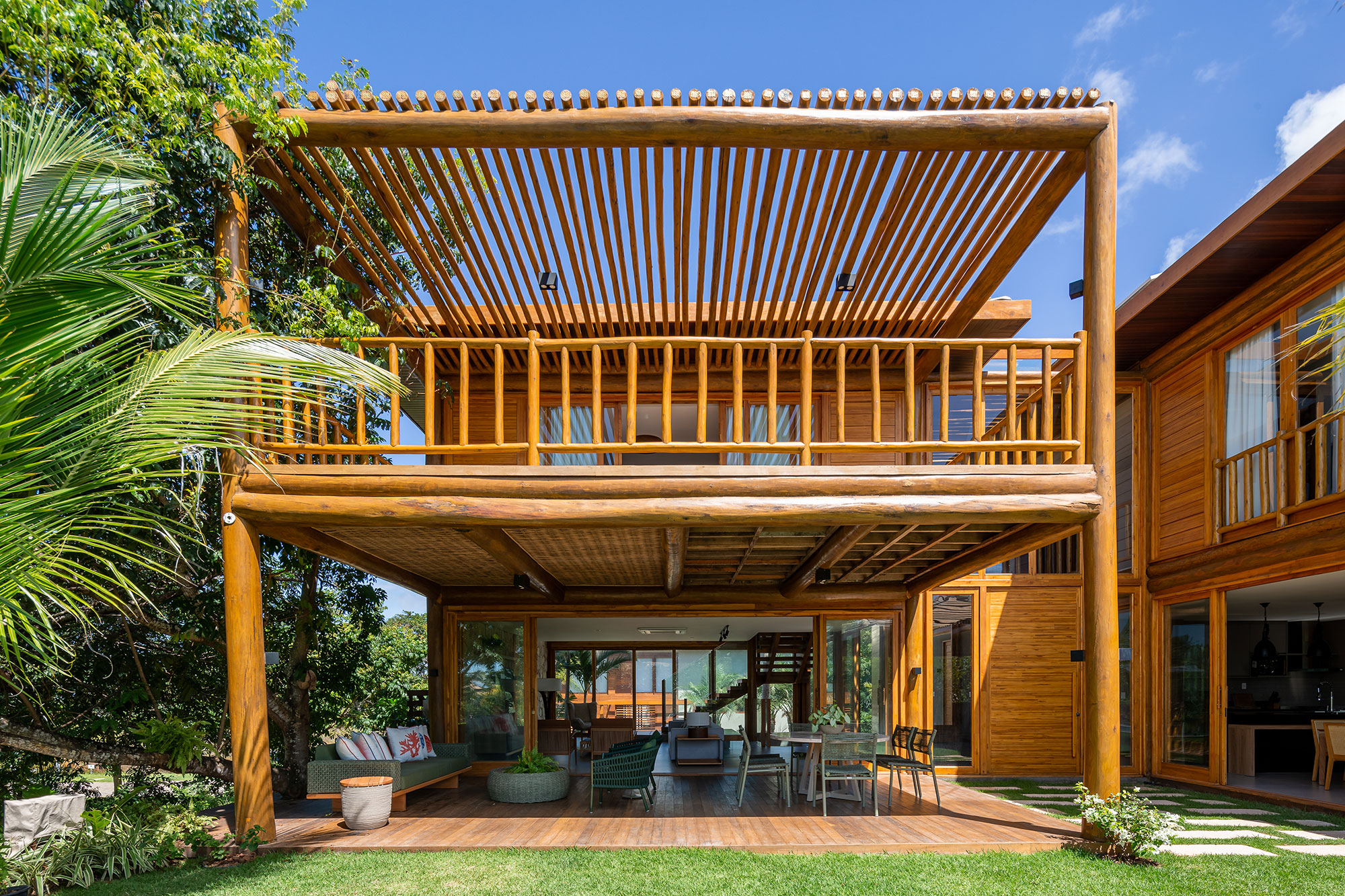 Casa na praia se integra à natureza com venezianas móveis na fachada. Projeto de Sidney Quintela. Na foto, varanda com jardim e pergolado.