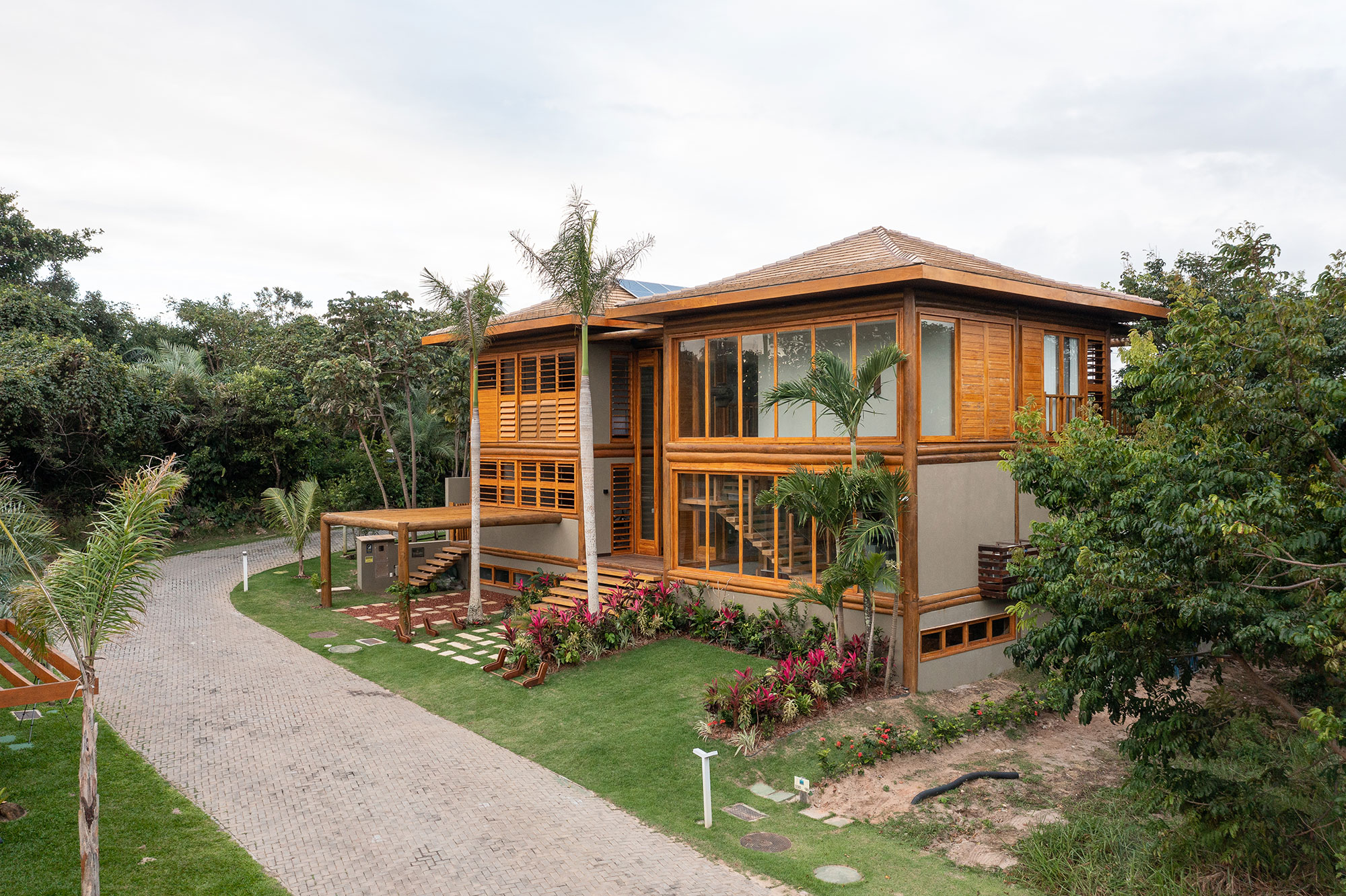 Casa na praia se integra à natureza com venezianas móveis na fachada. Projeto de Sidney Quintela. Na foto, fachada da casa com jardim.