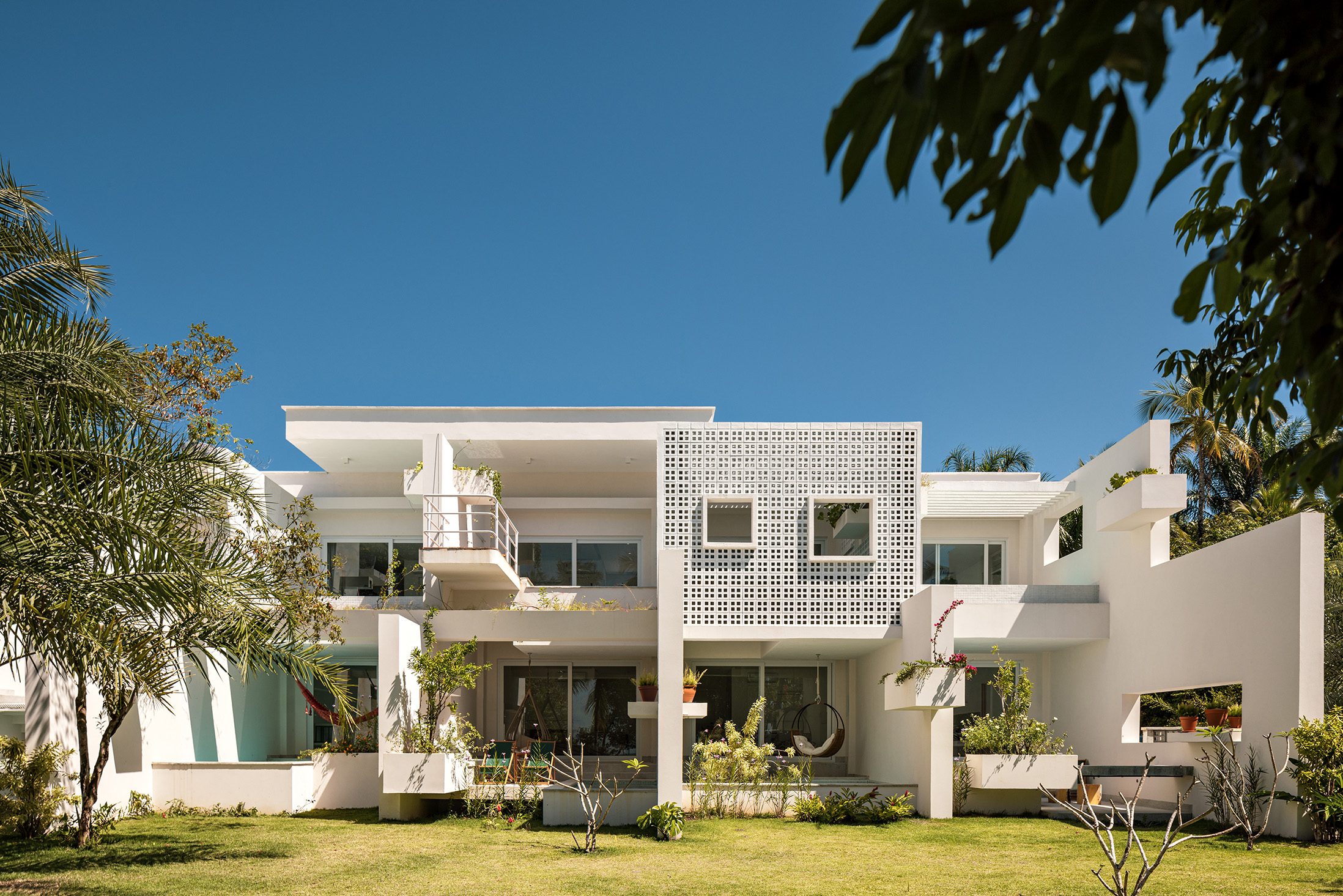 Pousada na Bahia possui 20 tipos diferentes de varandas privativas. Projeto de FGMF. Na foto, fachada da pousada com jardim e parede de cobogós.