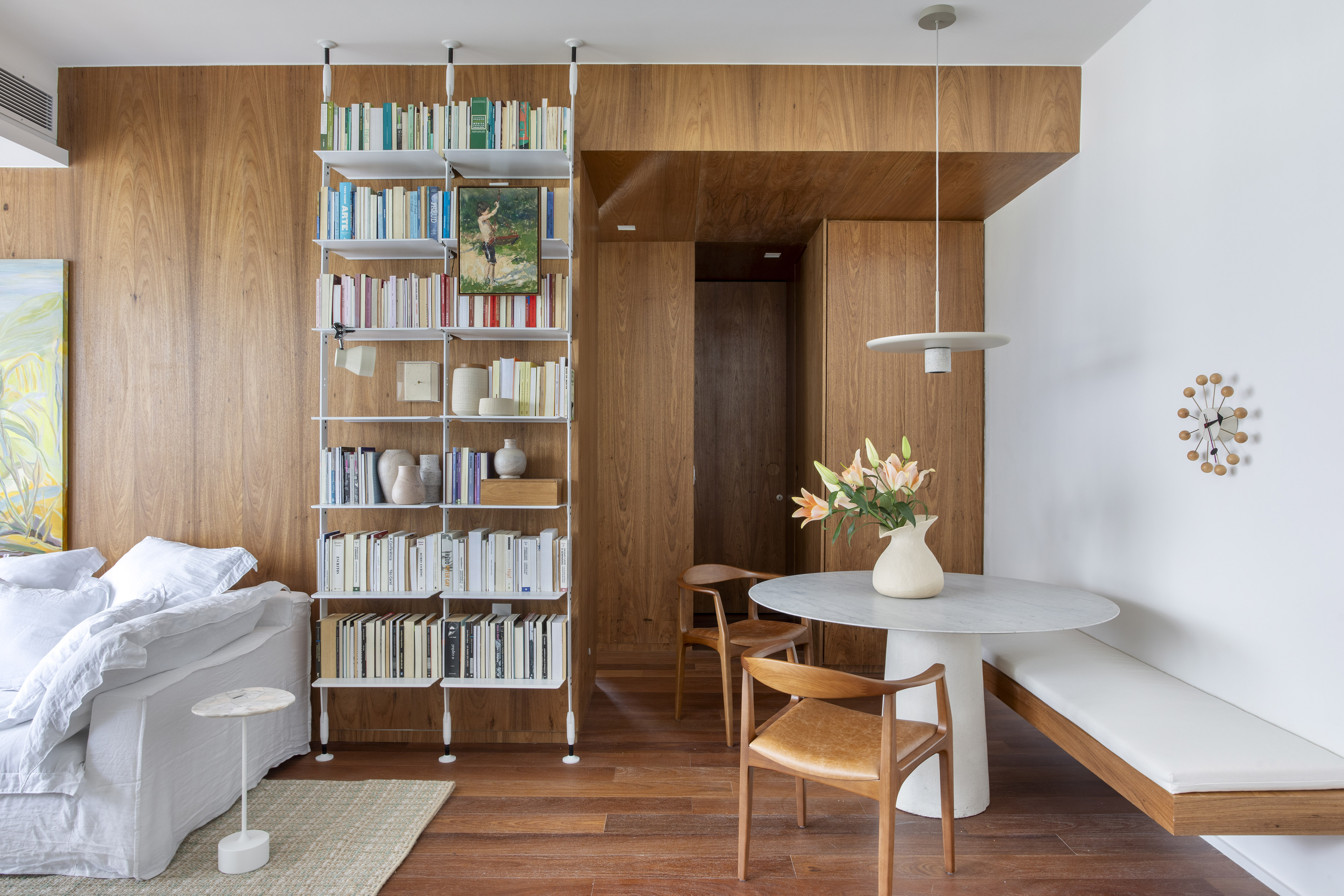 Apê de 80 m² ganha décor despojado, contemporâneo e bem carioca. Projeto de João Panaggio. Na foto, sala com canto alemão, estante e sofá.