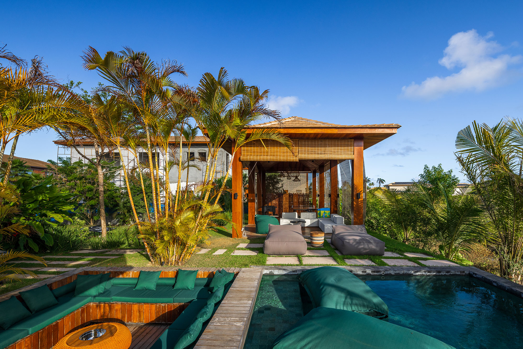 Grandes vãos integram esta casa de praia à natureza do entorno. Projeto de Sidney Quintela. Na foto, varanda com jardim, piscina e fogo de chão.