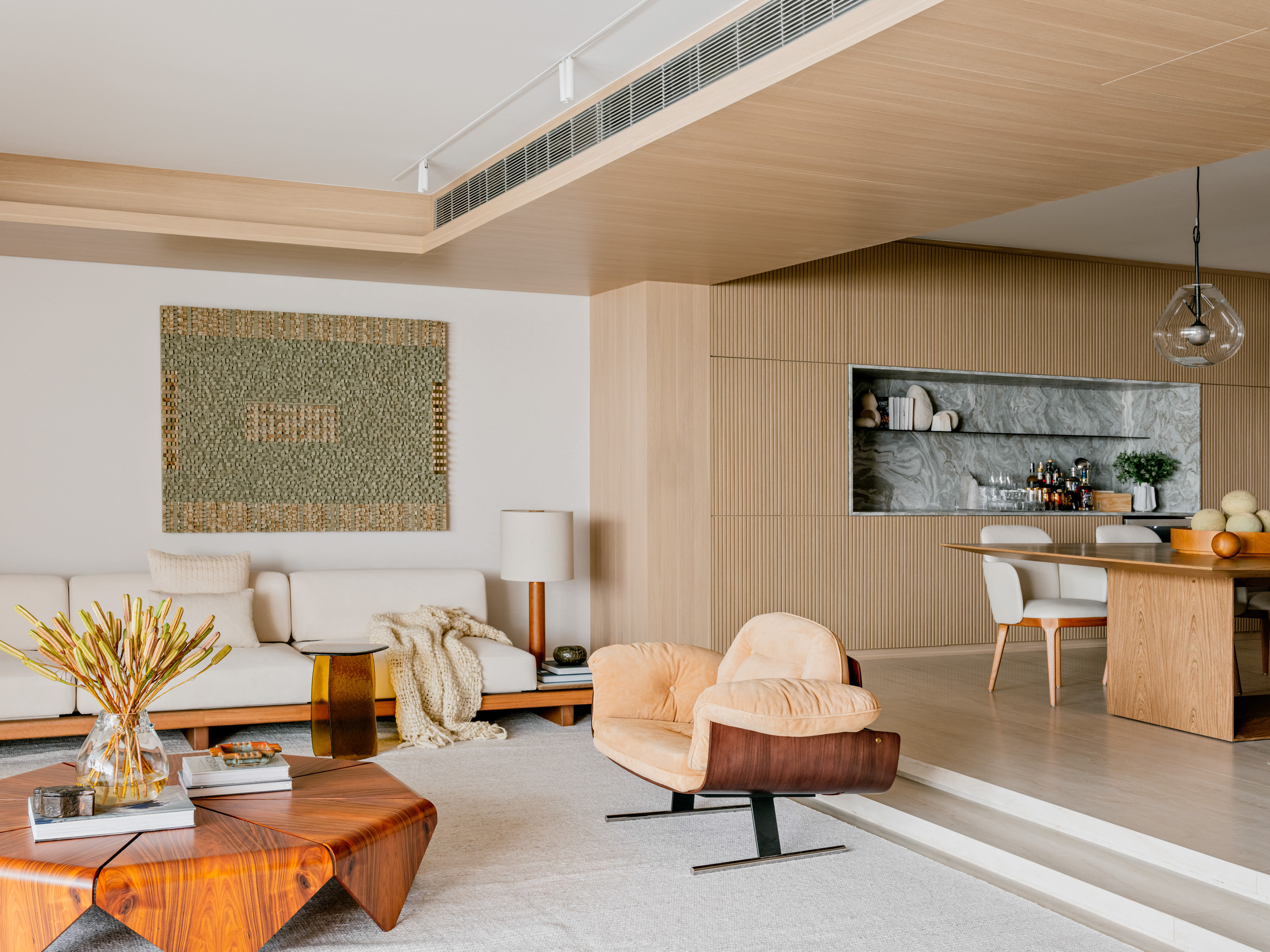 Apartamento antigo é modernizado sem perder o layout original. Projeto de Barbara Dundes. Na foto, sala de estar com sofá, quadro e tapete. Sala de jantar com bar.