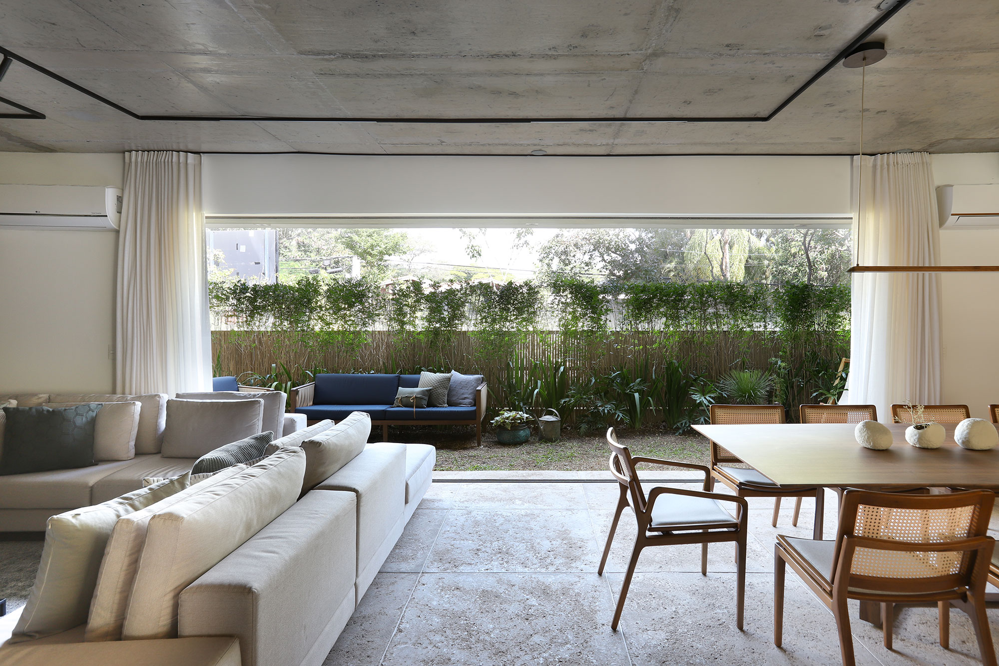 Apartamento garden ganha três áreas de jardim nas varandas. Projeto de Mandril Arquitetura. Na foto, cozinha com ilha e mesa de refeição. Sala de jantar e estar integradas.