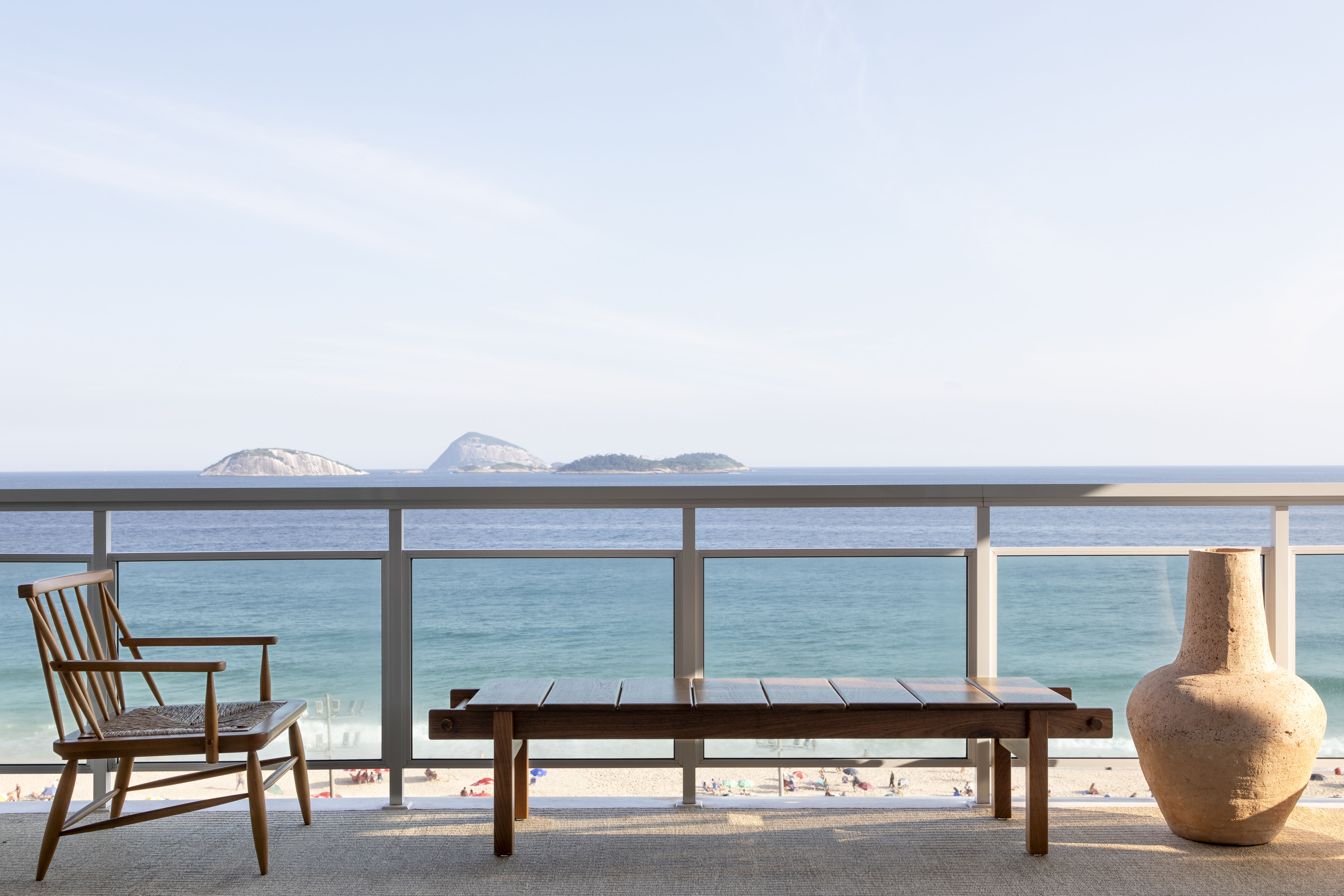 Apê alugado vira pied-à-terre em frente ao mar de Ipanema. Projeto de PKB Arquitetura. Na foto, varanda com banco e vista para o mar.