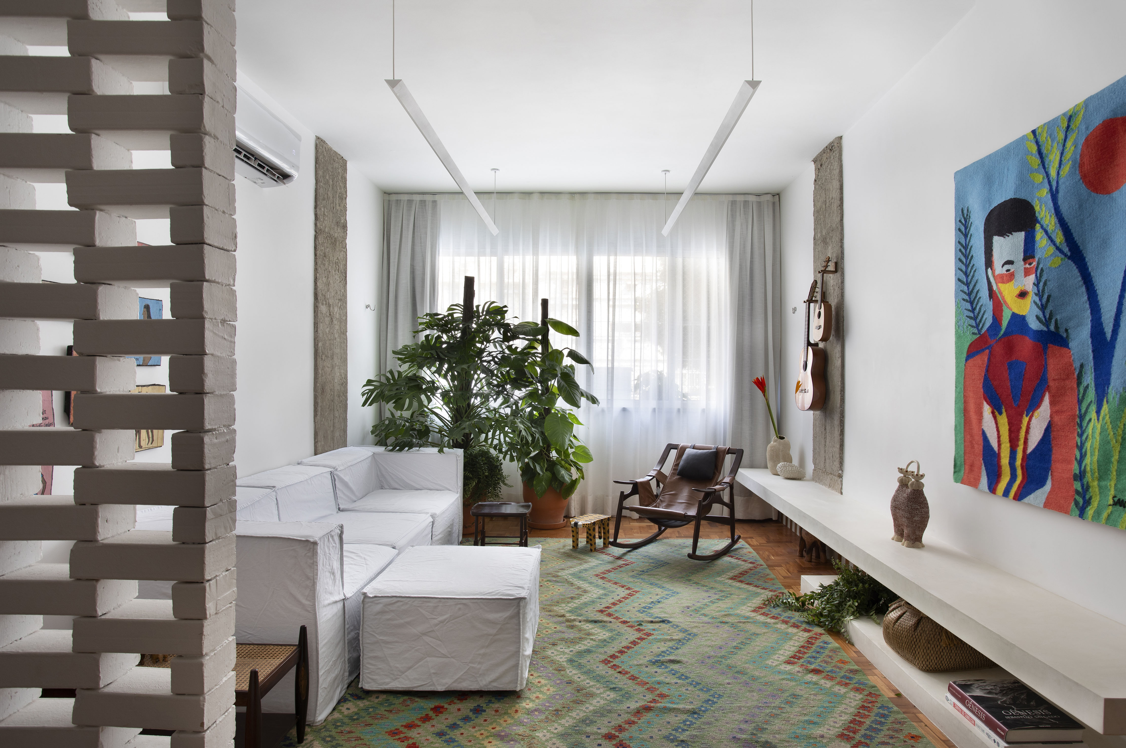 Apê é projetado para ser o lar perfeito da infância das filhas da família. Projeto de Bric Arquitetura. Na foto, sala de estar com tapete, quadro e poltona.