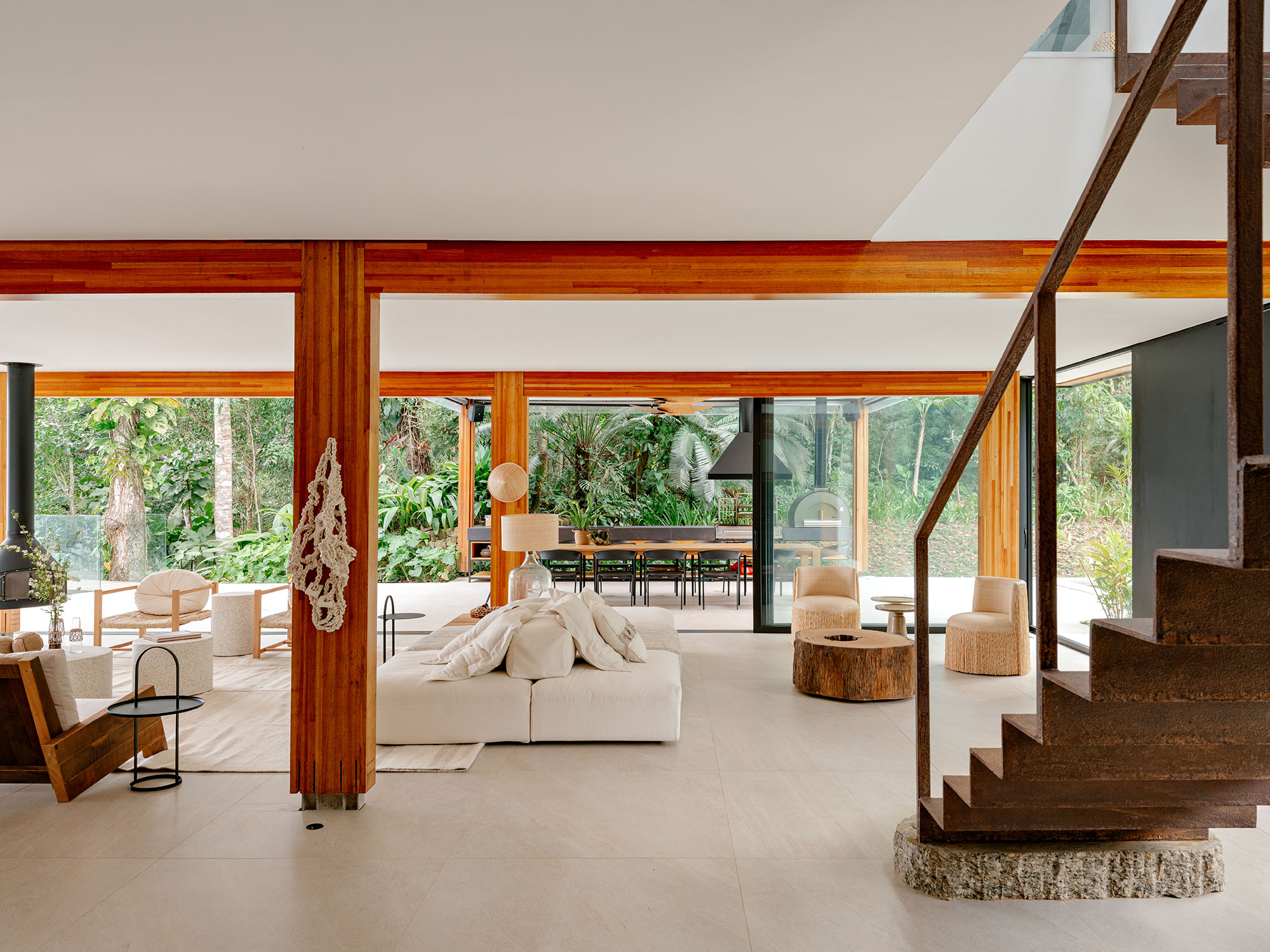 Casa de praia sustentável vira refúgio no meio da Mata Atlântica. Projeto de Patrícia Martinez. Na foto, sala com escada e vista para o jardim.