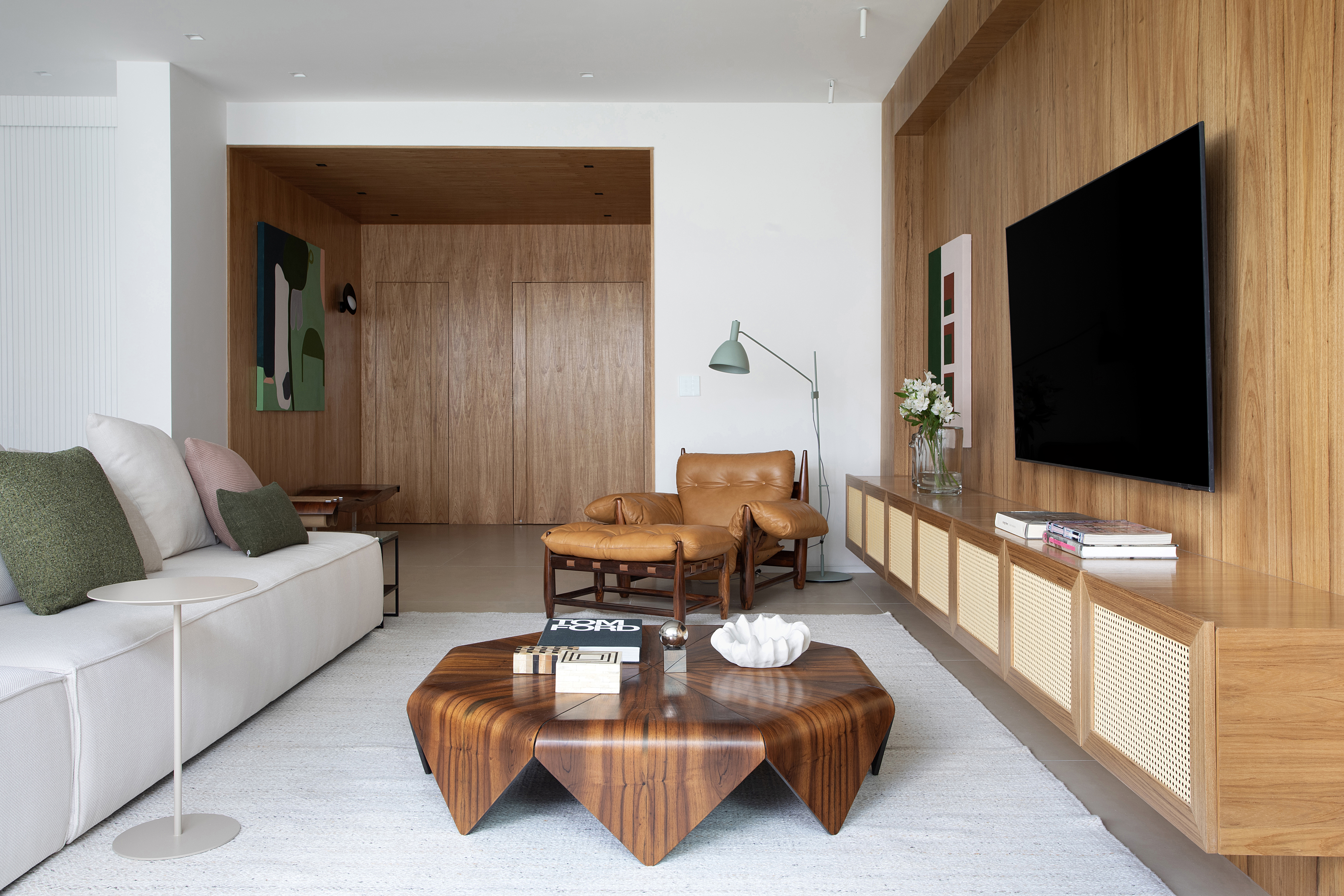Apartamento dos anos 1960 ganha décor modernista e repleto de design. Projeto de Beta Arquitetura. Na foto, sala com tv, sofá e poltrona.
