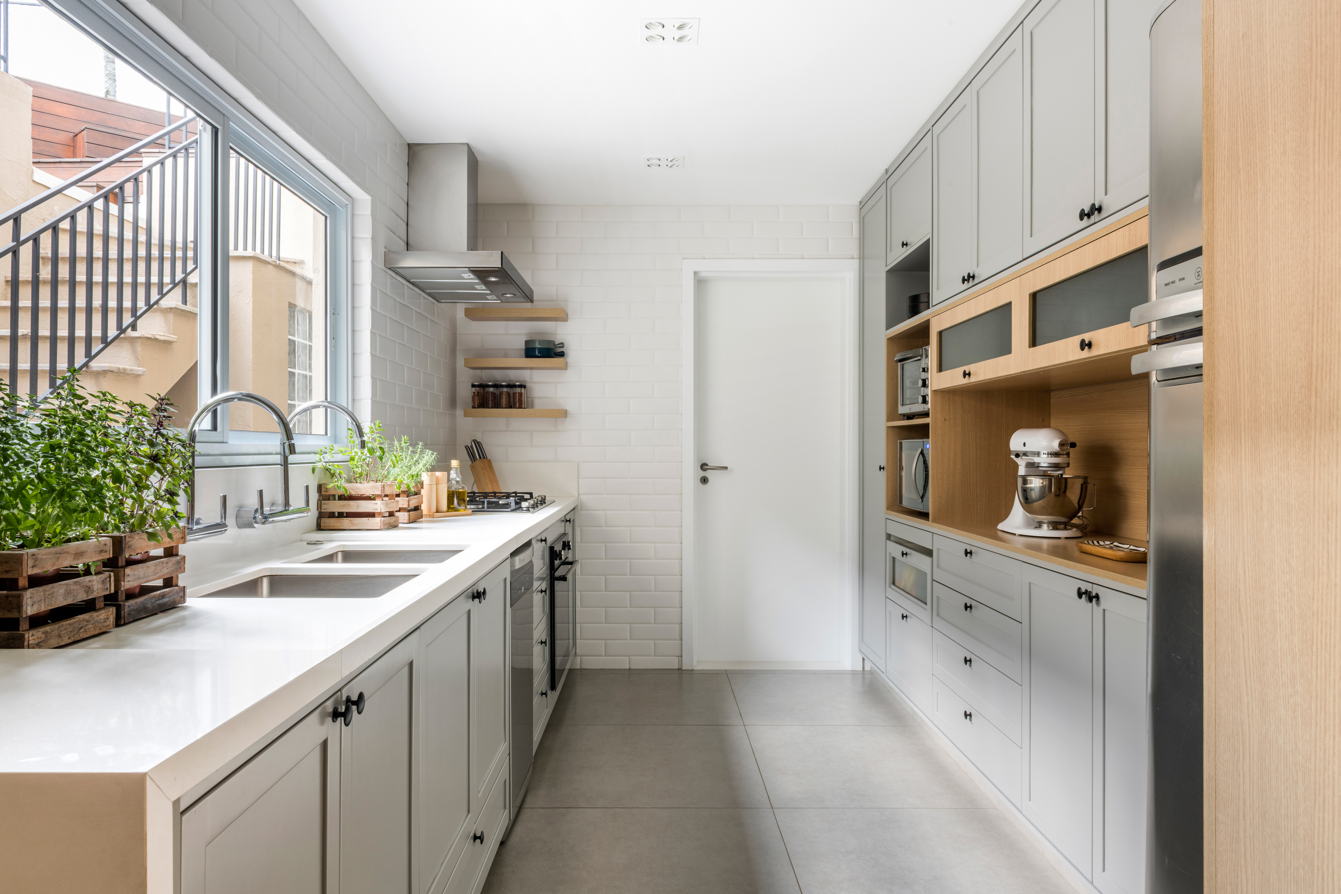 Casa com cozinha integrada tem marcenaria sob medida e materiais naturais. Projeto de Ricardo Abreu. Na foto, cozinha com marcenaria cinza e subway tiles.