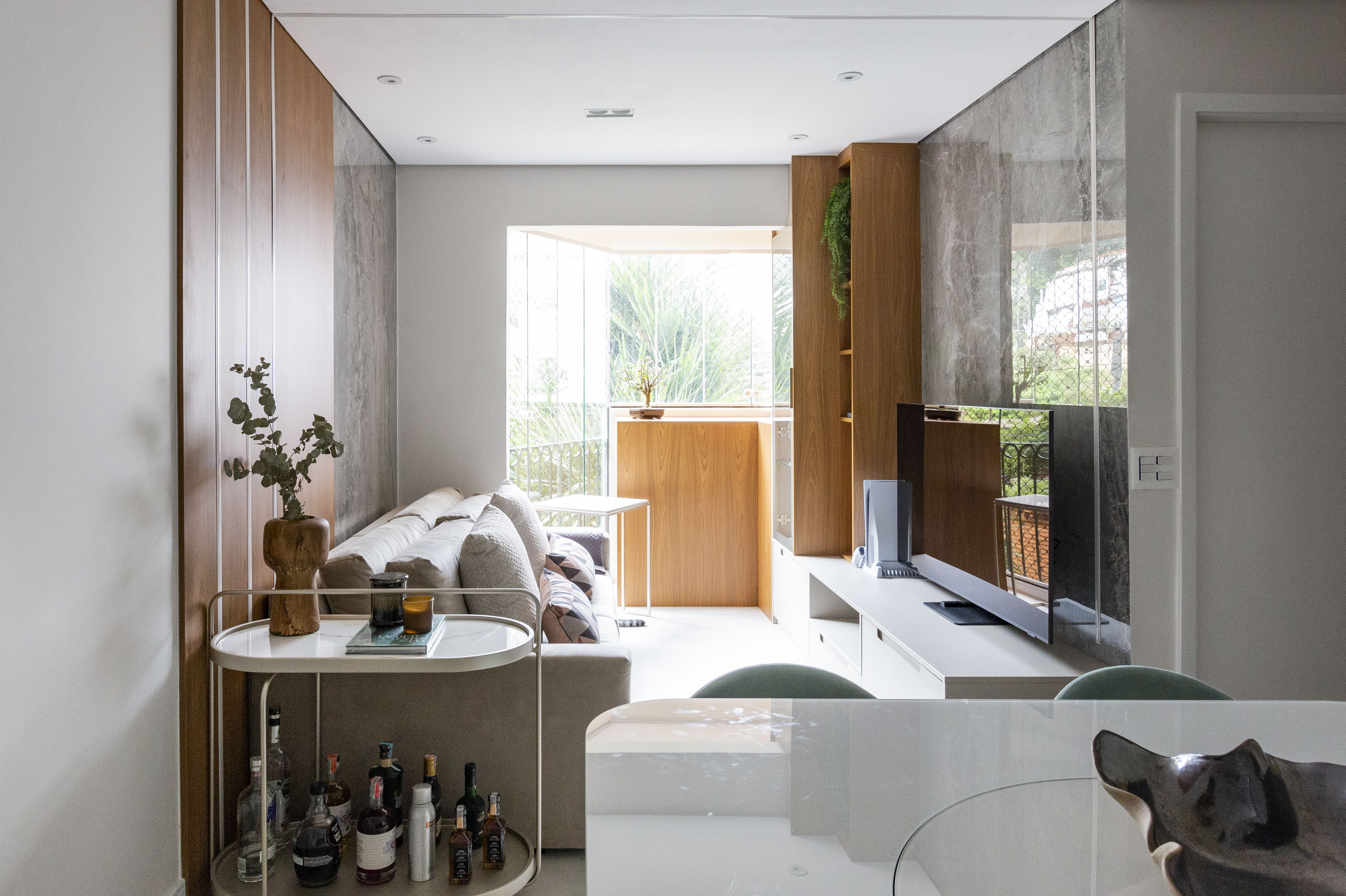 Com 76 m², apê ganha décor moderno pensado para os gatos da família. Projeto de Daniela Funari. Na foto, sala integrada com a cozinha com tv e bar.