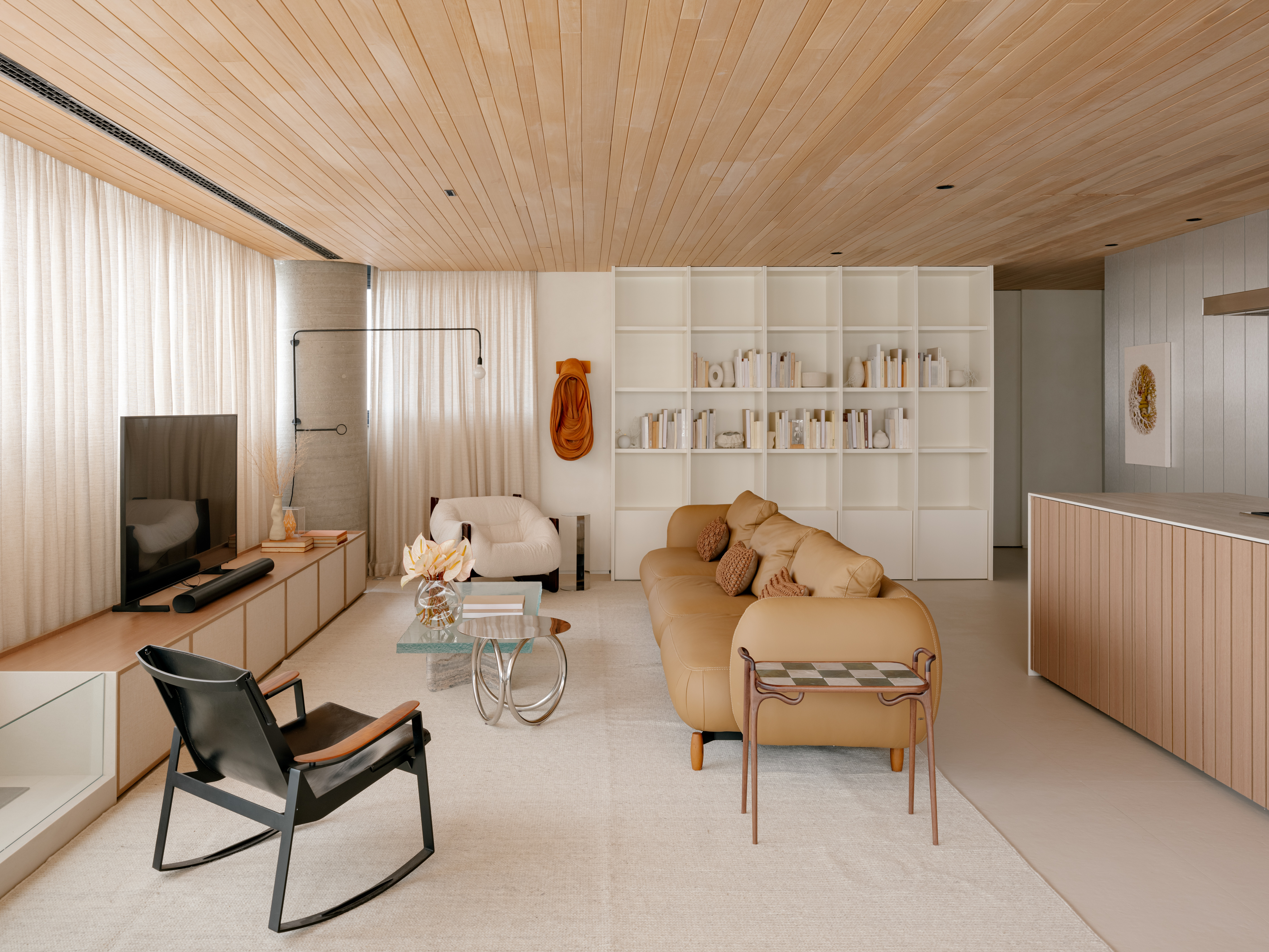 Conheça o apartamento de arquiteta Bárbara Dundes em São Paulo. Na foto, sala com teto de madeira, tapete e tv,