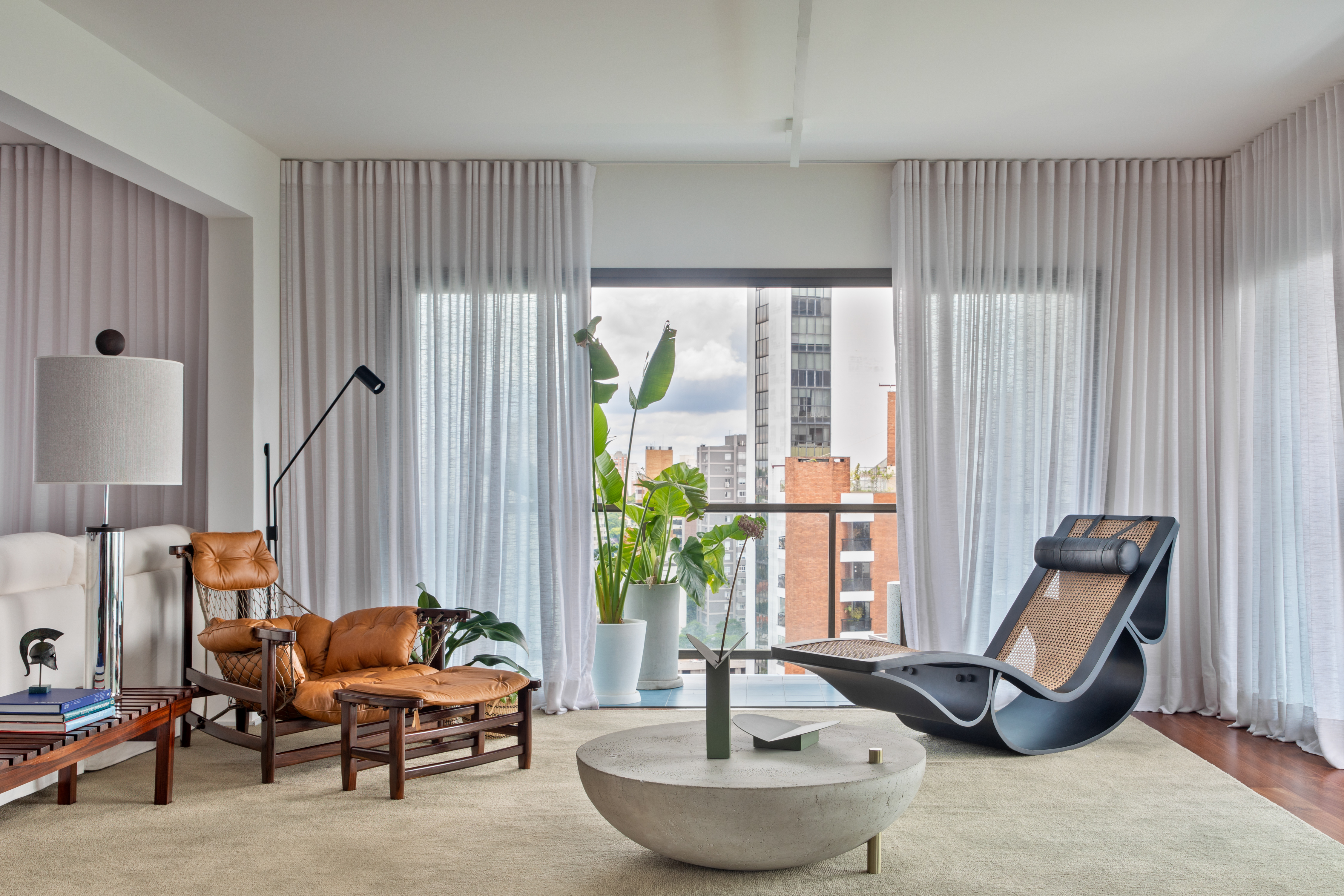 Obras de arte e revestimentos conferem cor a projeto de 300 m². Projeto de Rodra Arquitetura, Na foto, sala com poltrona, varanda e mesa de centro.