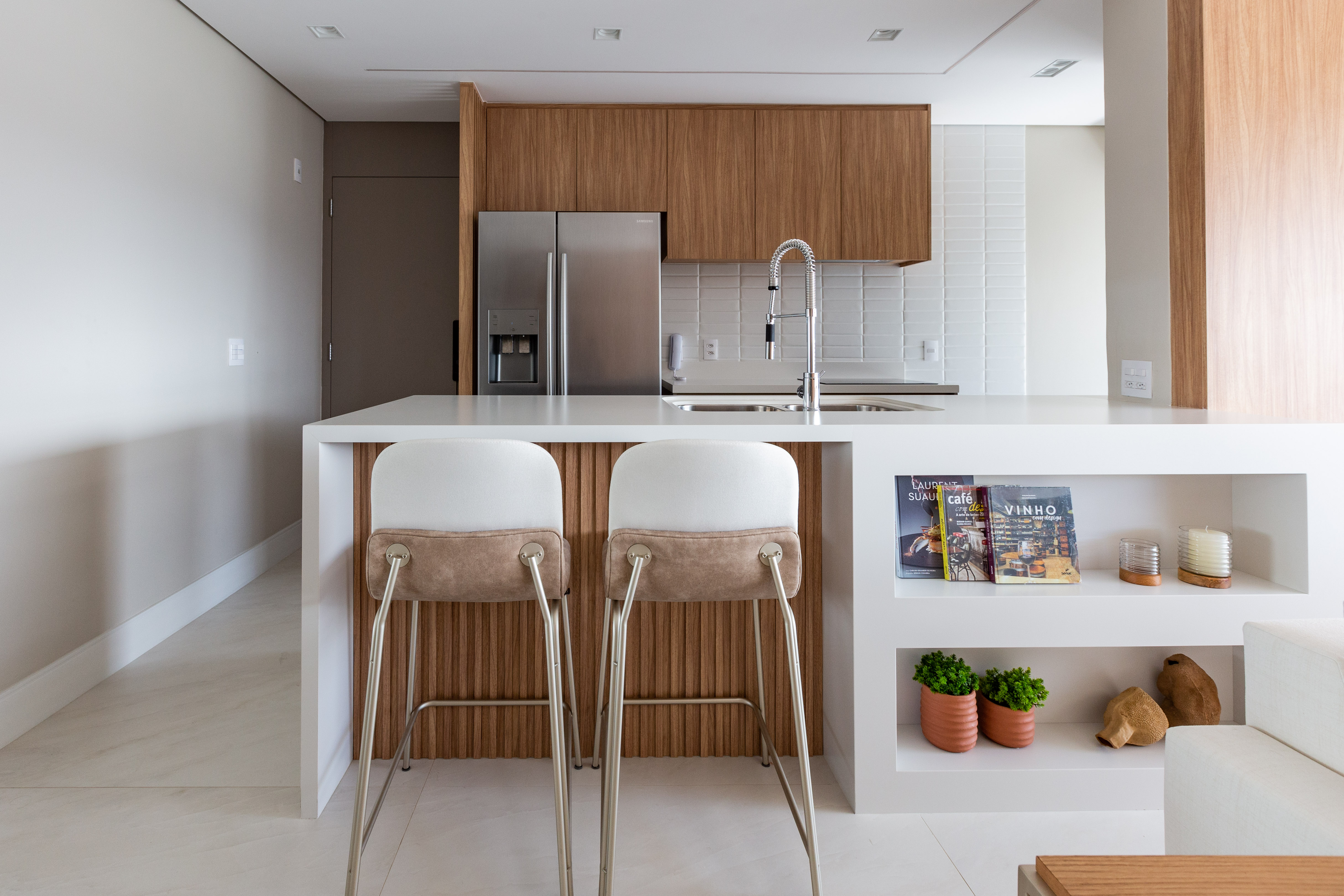 Portas mimetizadas e tons off white marcam décor de apê de 104 m². Projeto de Daniela Funari. Na foto, sala integrada com cozinha e ilha.