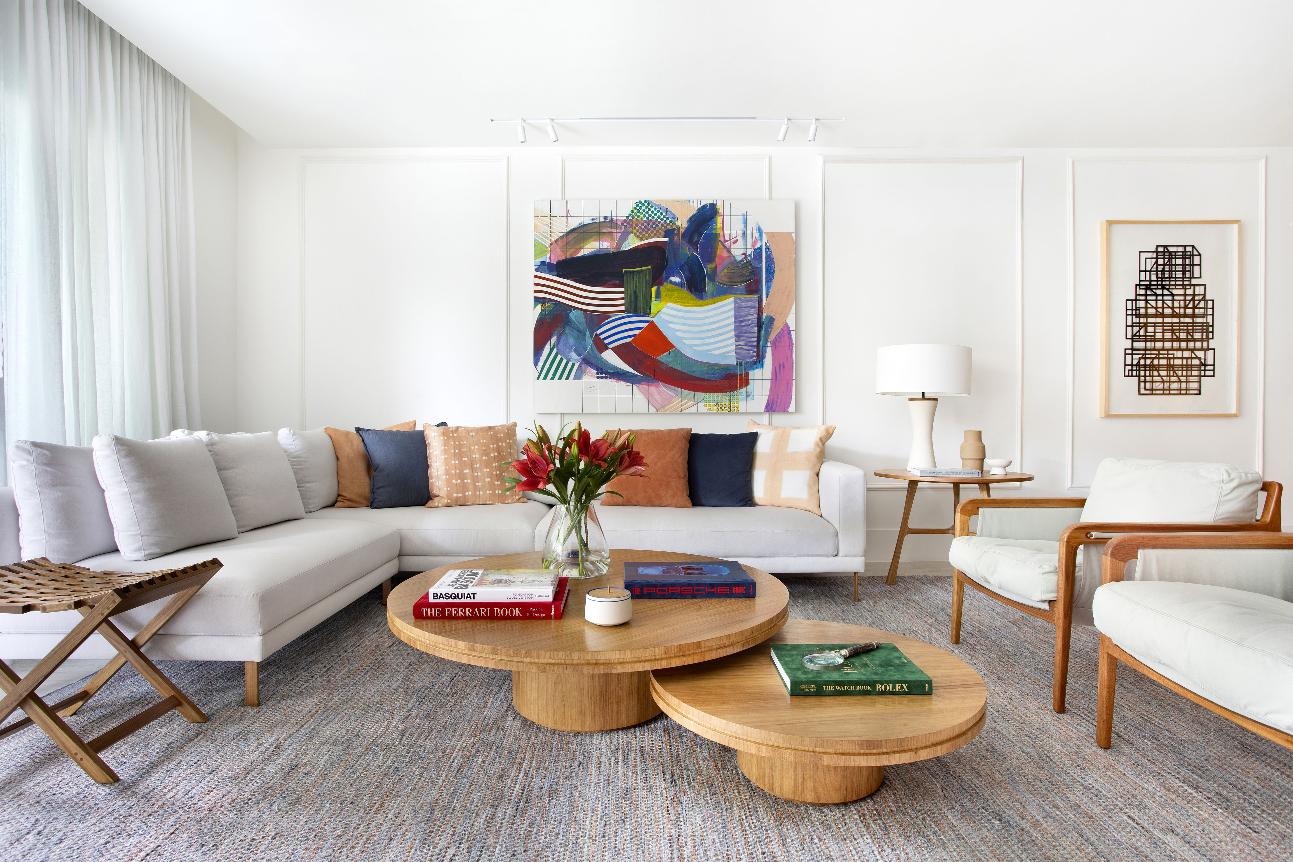 Madeira, móveis assinados e obras de arte dão o tom a este apê de 170 m². Projeto de Cristina Bezamat. Na foto, sala de estar com varanda, sofa em L e quadros.