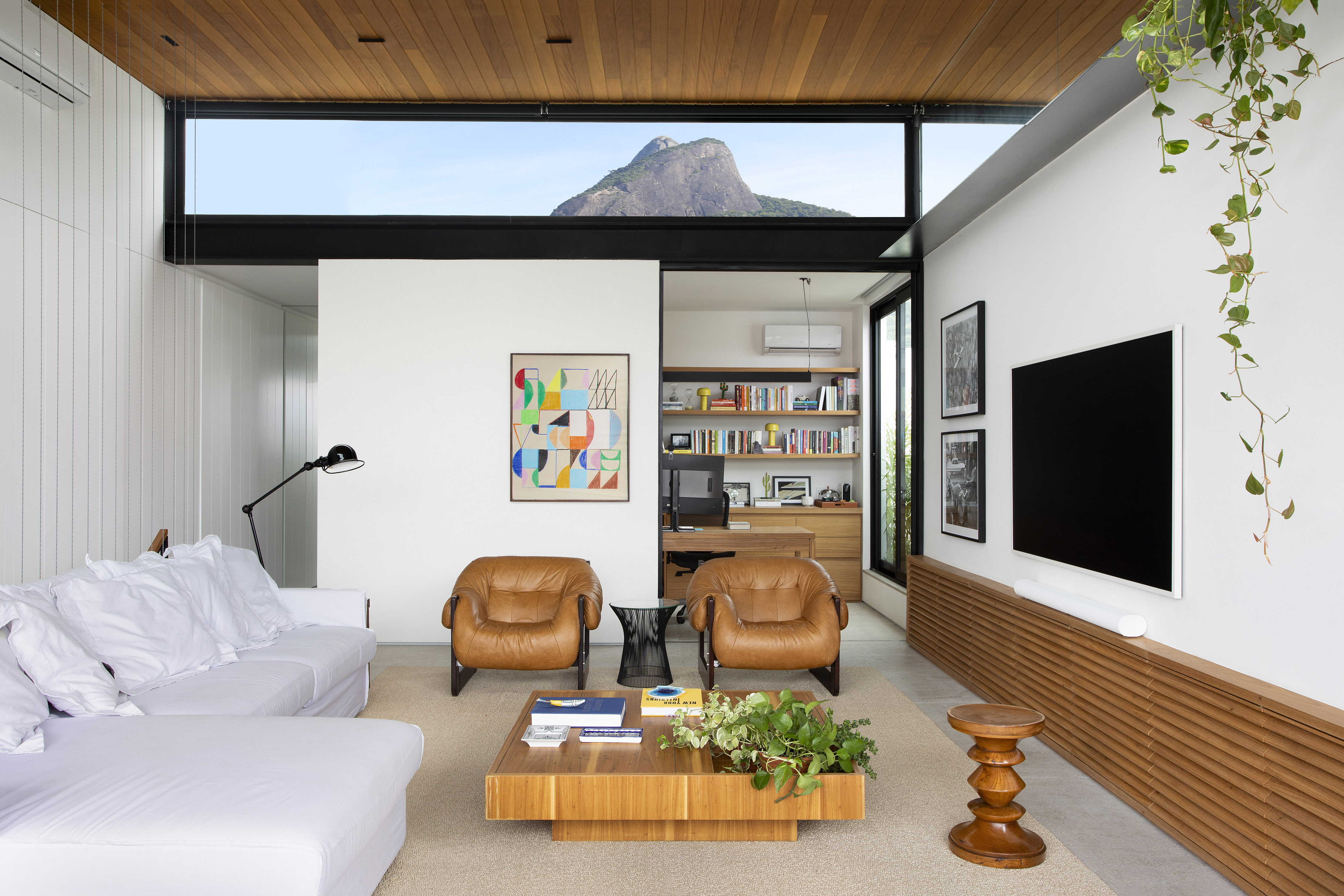 Morro Dois Irmãos é enquadrado nas janelas desta cobertura duplex. Projeto de Escala Arquitetura. Na foto, sala com vista para o morro e poltronas.