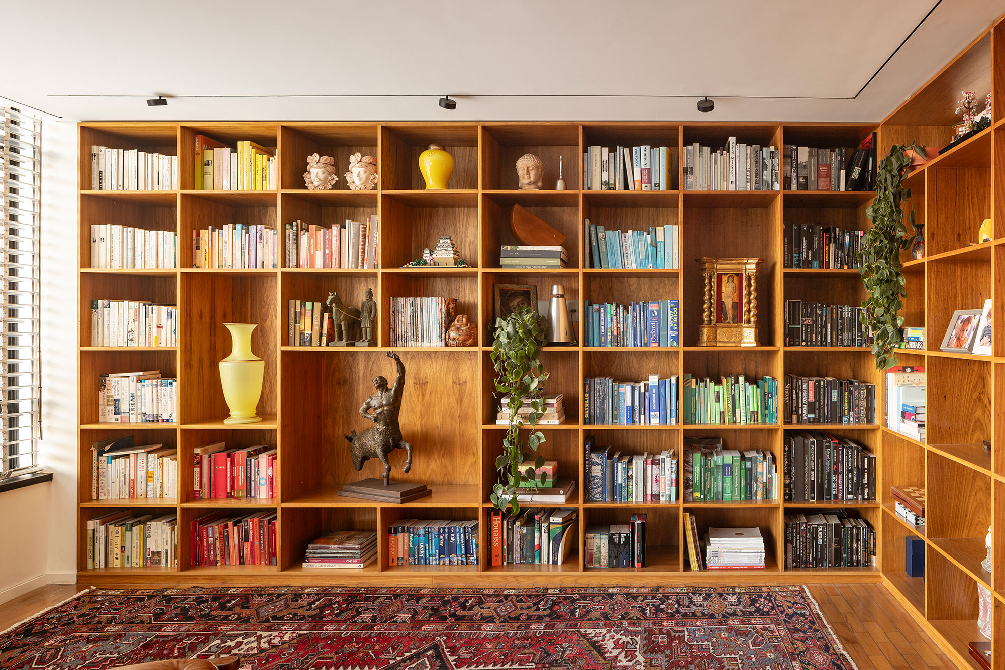 Coleção de arte guia reforma de apartamento brasiliense da década de 1960. Projeto de BLOCO Arquitetos. Na foto. sala com estante e tapete.