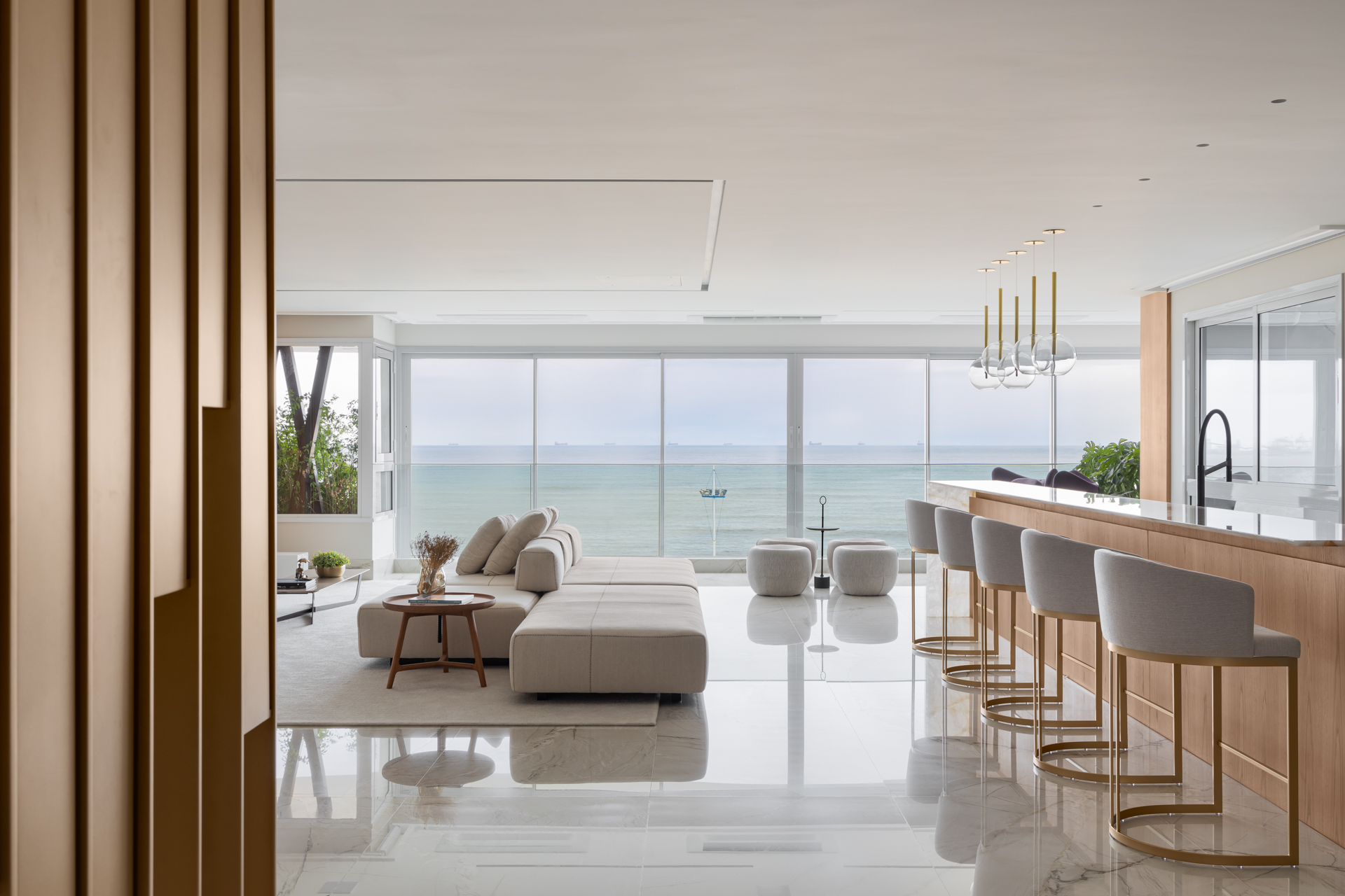 Dois apês unidos criam lar contemporâneo com vista privilegiada para o mar. Projeto de Daniela Andrade. Na foto, sala com vista para o mar e sofá-ilha.