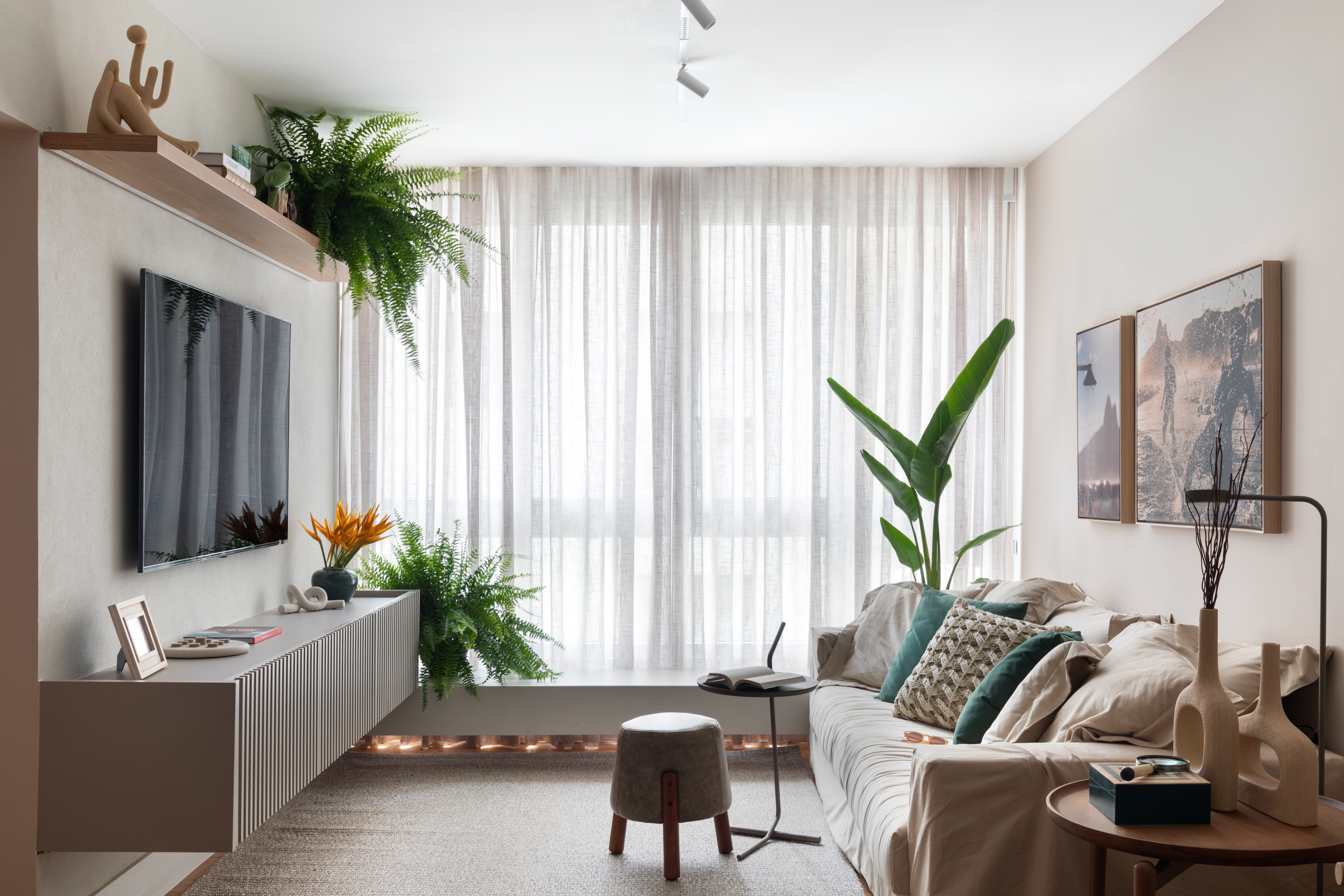 Apê de 92 m² no Leblon vira refúgio com clima carioca. Projeto de Amanda Miranda. Na foto, sala com tv e banco na janela.