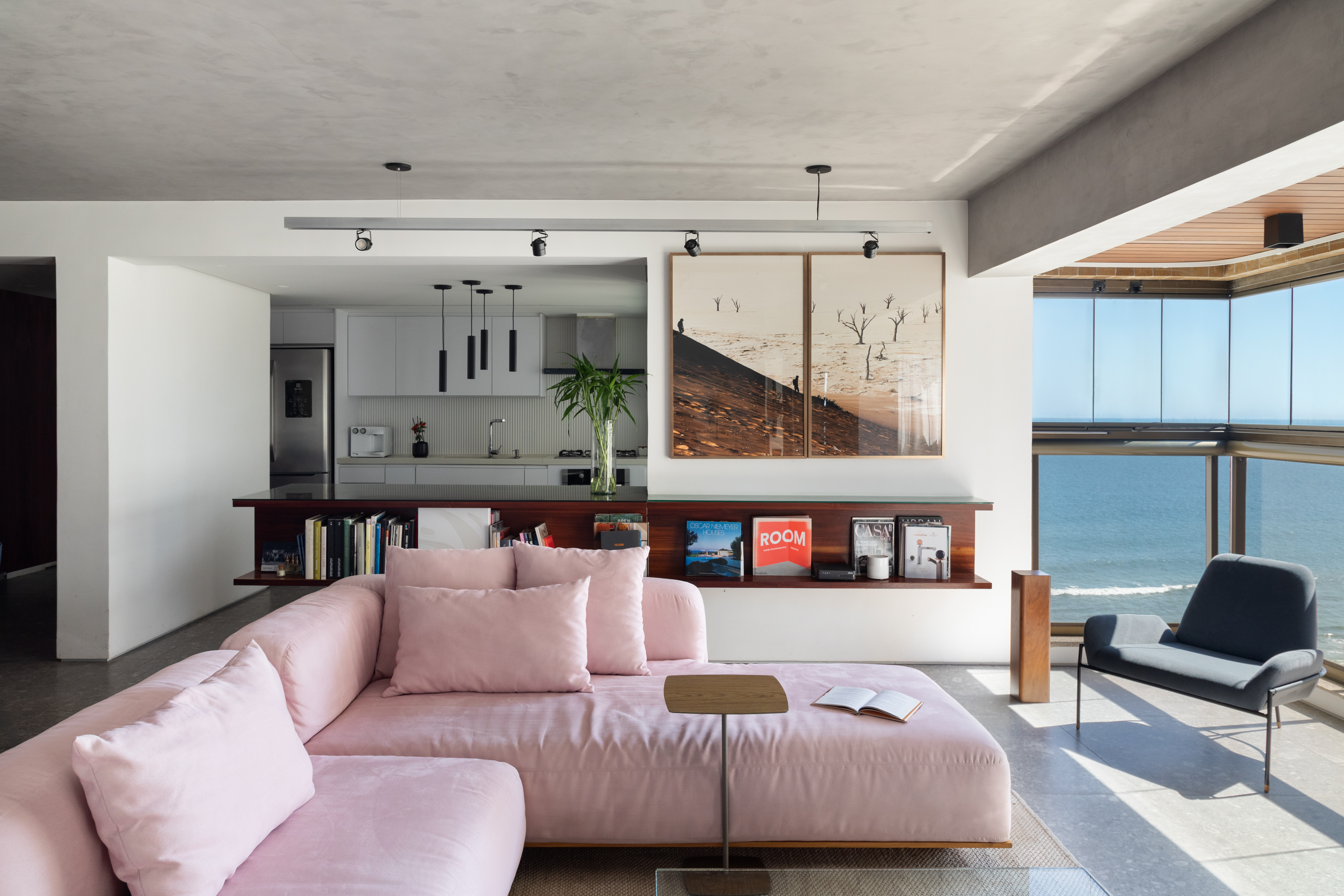 Conheça o apê - com vista para o mar! - do arquiteto Rodrigo Cardoso. Na foto, sala com vista para o mar, aparador e sofá rosa.