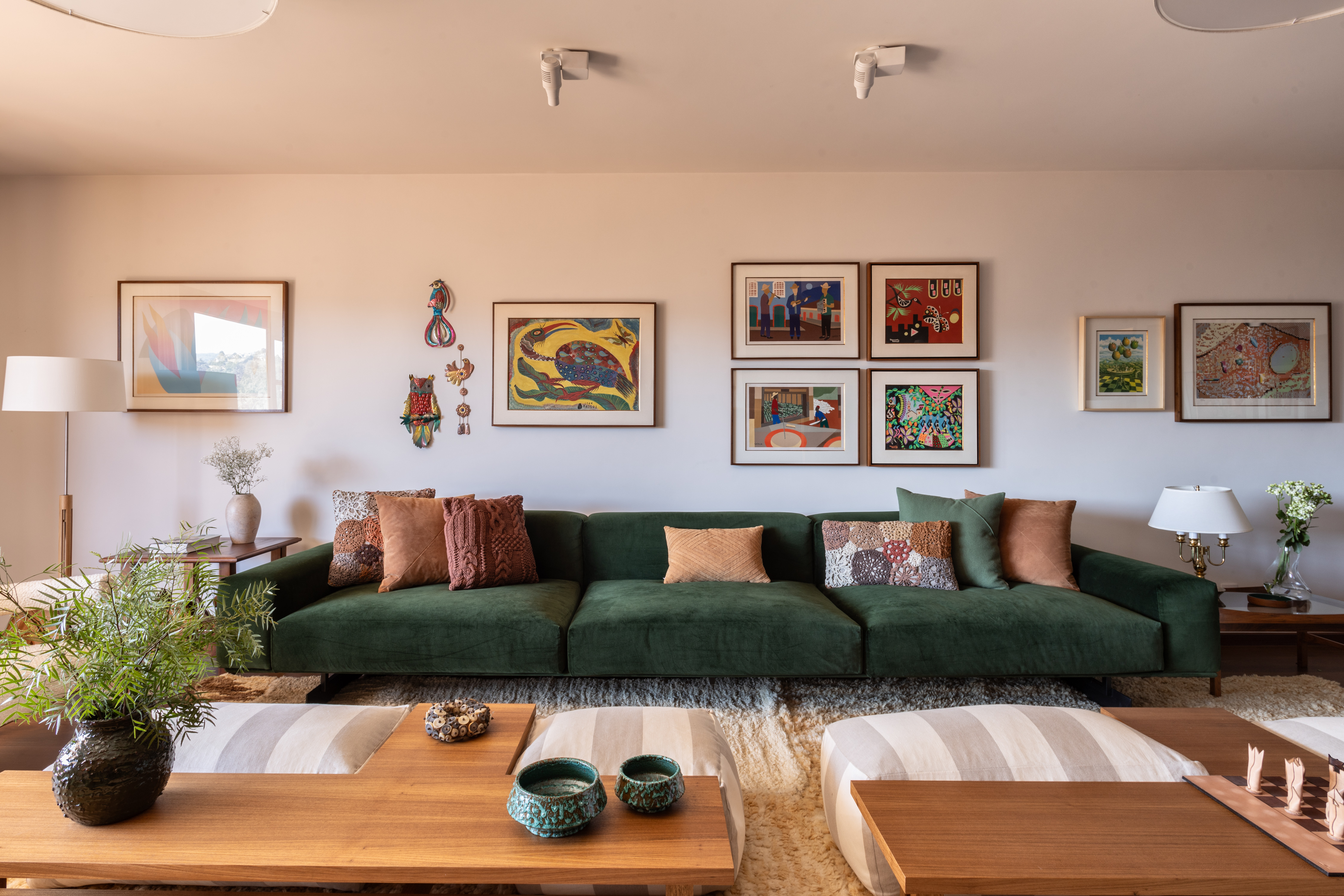 Apartamento de campo ganha décor afetivo com itens da década de 1980. Projeto de Felipe Carolo. Na foto, sala de estar com quadros e sofá verde.