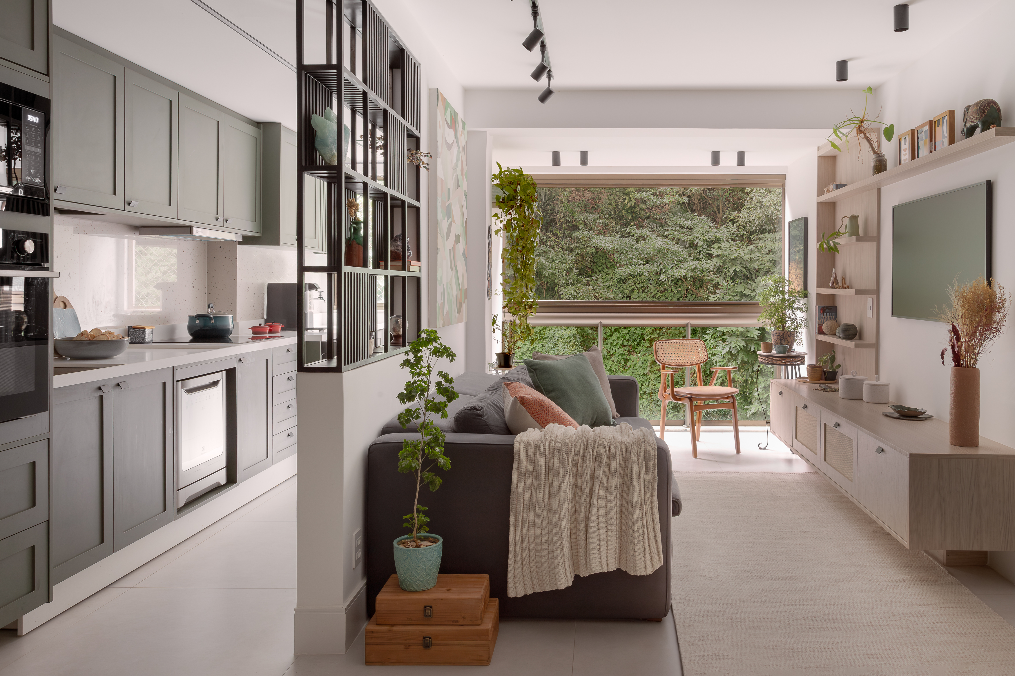 Plantas diversas trazem a natureza para dentro deste apê de 80 m². Projeto de Ana Cano. Na foto, sala integrada com a cozinha e marcenaria verde.